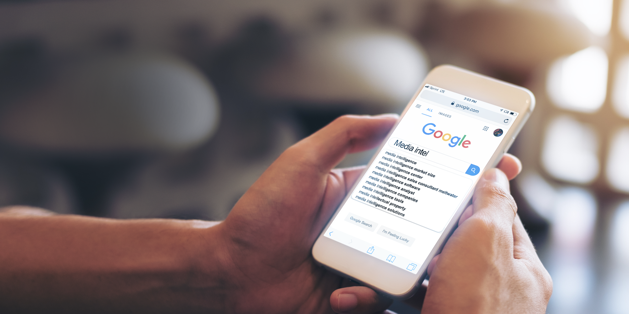 Hands holding a smartphone displaying a Google search for Media Intelligence