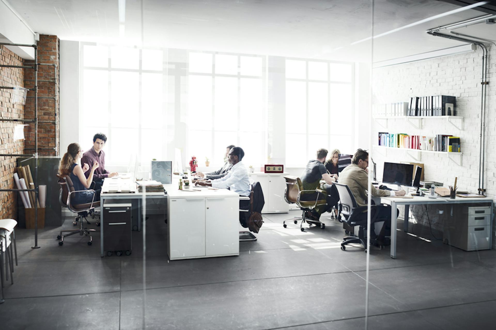 Foto Büro mit arbeitenden Menschen durch eine Glaswand fotografiert