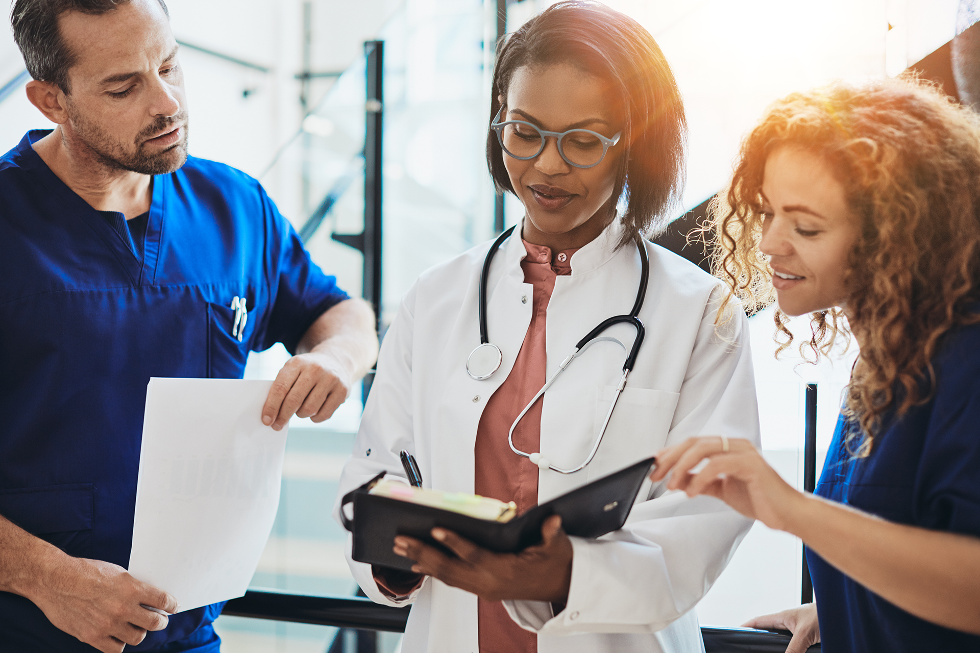 Three healthcare professionals, two nurses and a doctor, look at a notebook in this image for Meltwater's 2023 Industry Snapshot: Healthcare