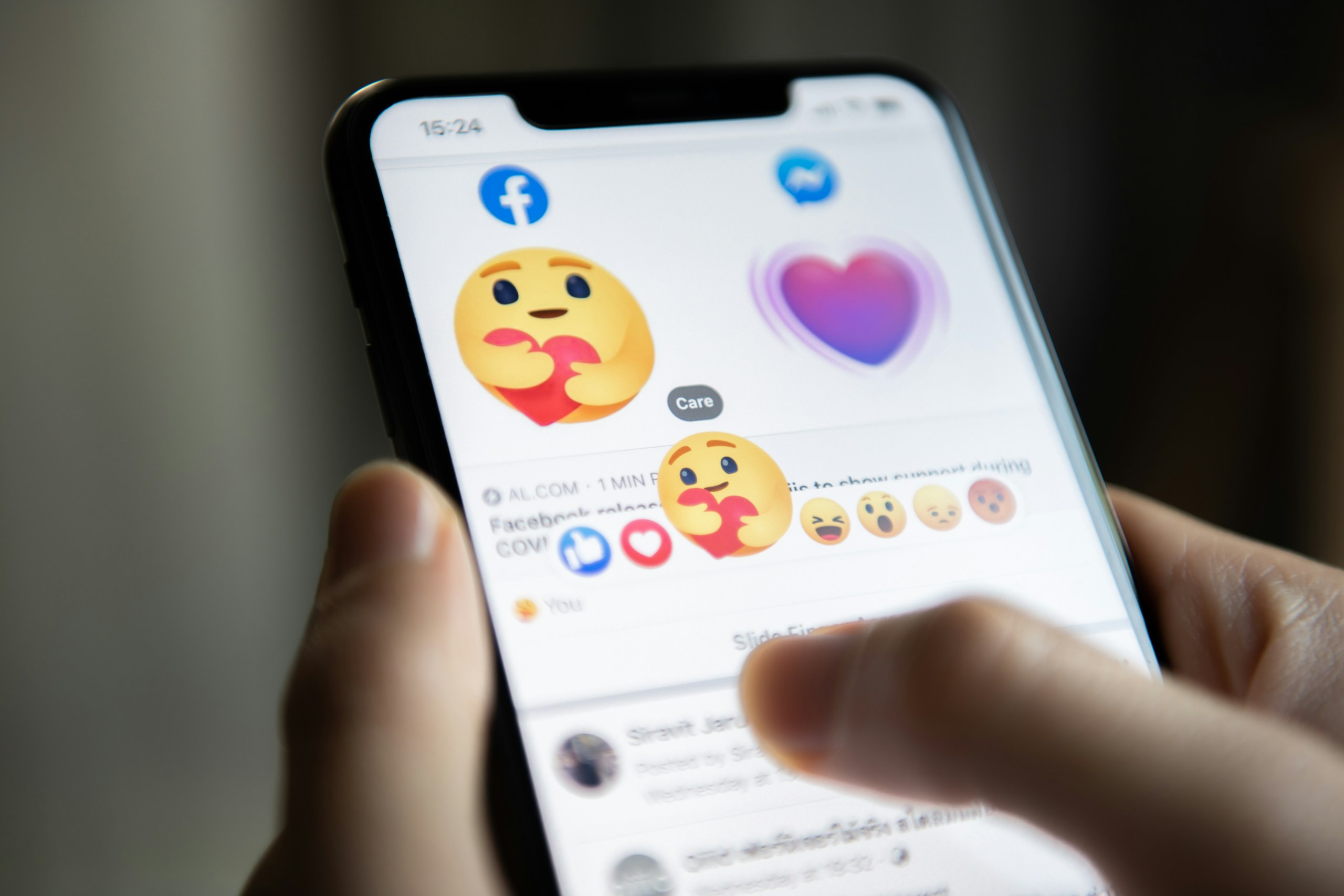 Photo de quelqu'un qui tient son téléphone avec l'application Facebook ouverte et des emojis