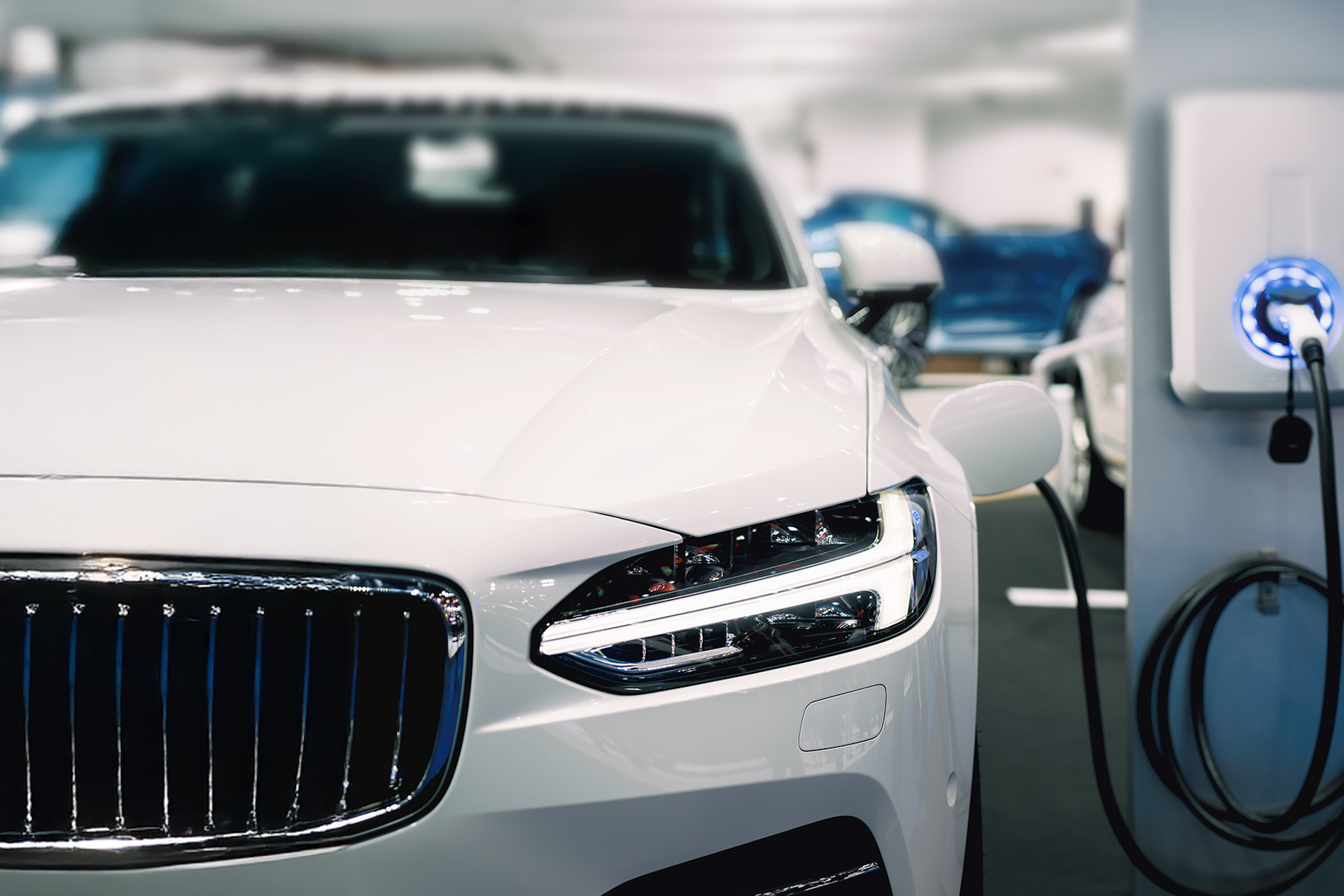 Une voiture blanche branchée sur une borne de recharge blanc argenté pour le rapport Consumer Insights : Véhicules électriques de Meltwater.