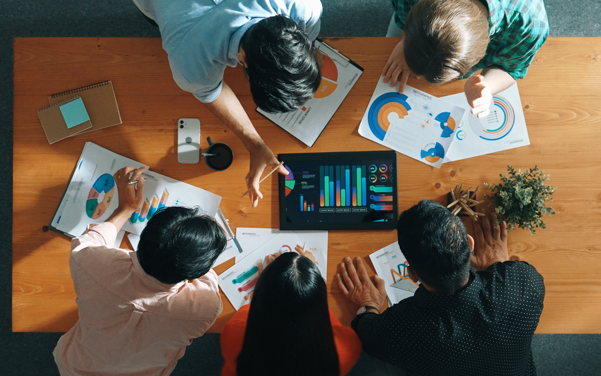 A group of office workers looking at analytics charts on a tablet computer. 