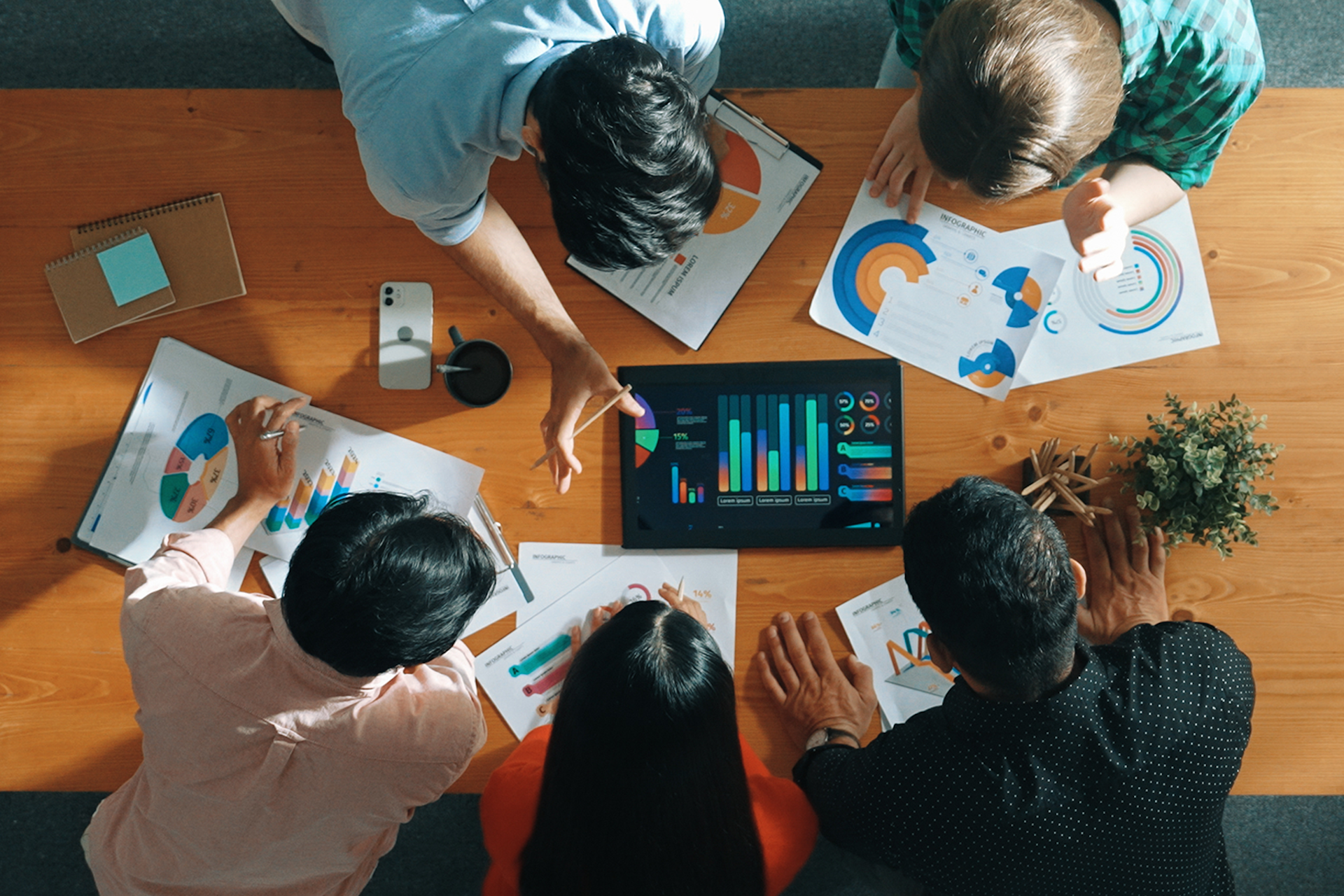 A group of office workers looking at analytics charts on a tablet computer.