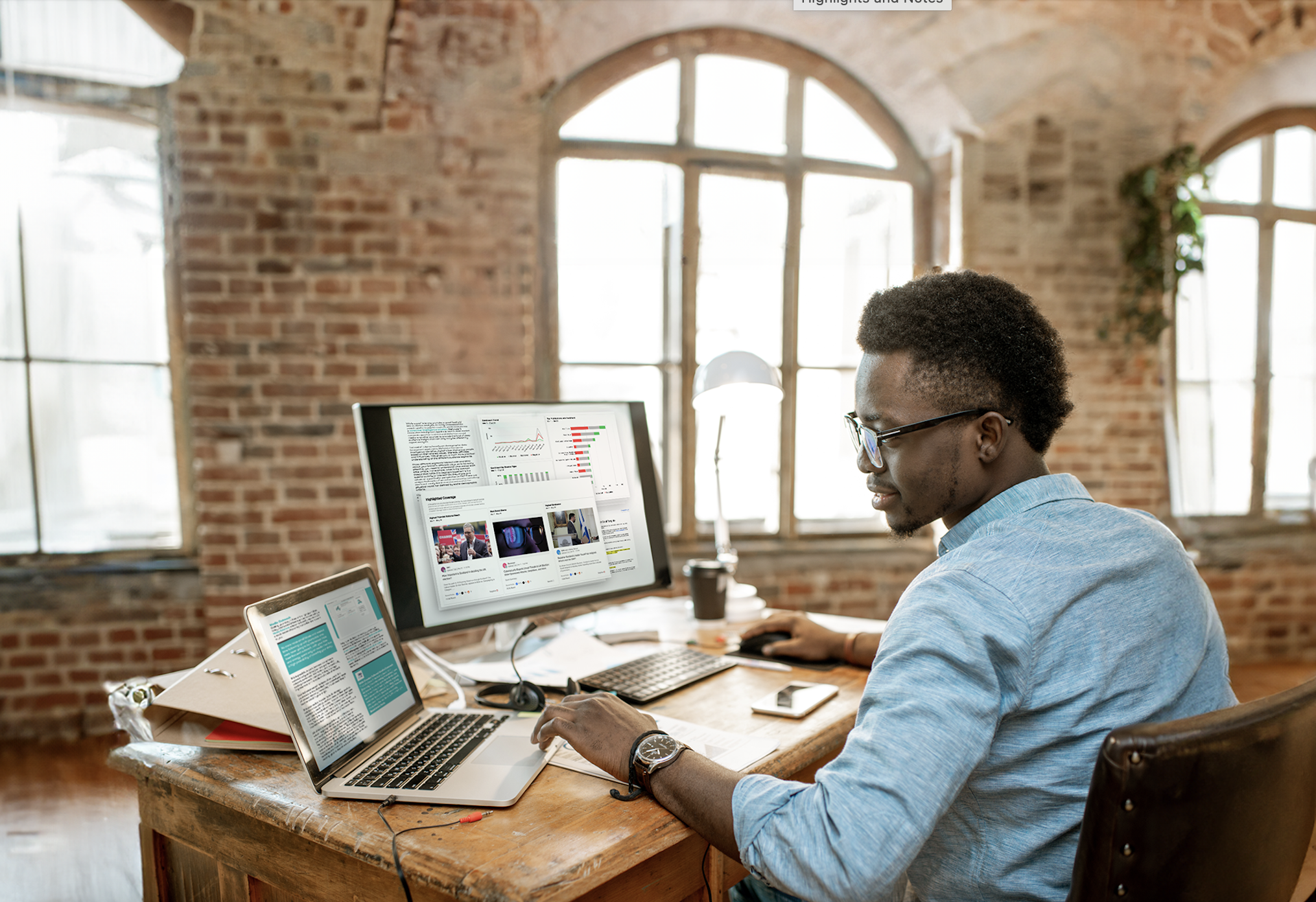Image d'un professionnel des relations publiques assis à son bureau devant un grand écran et un ordinateur portable. Les ordinateurs affichent divers tableaux et outils destinés aux professionnels des relations publiques. Téléchargement de PR Toolkit