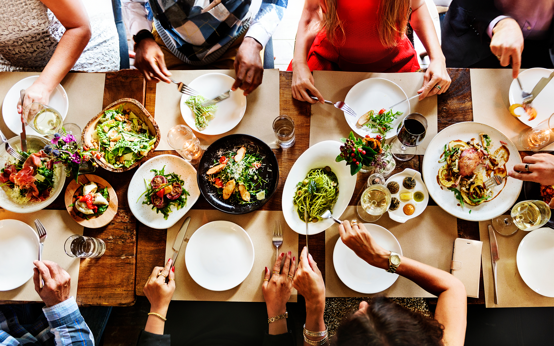 People seated at a dining table full of plates of food in this image for Meltwater's 2024 Consumer Insights: Food & Beverage report