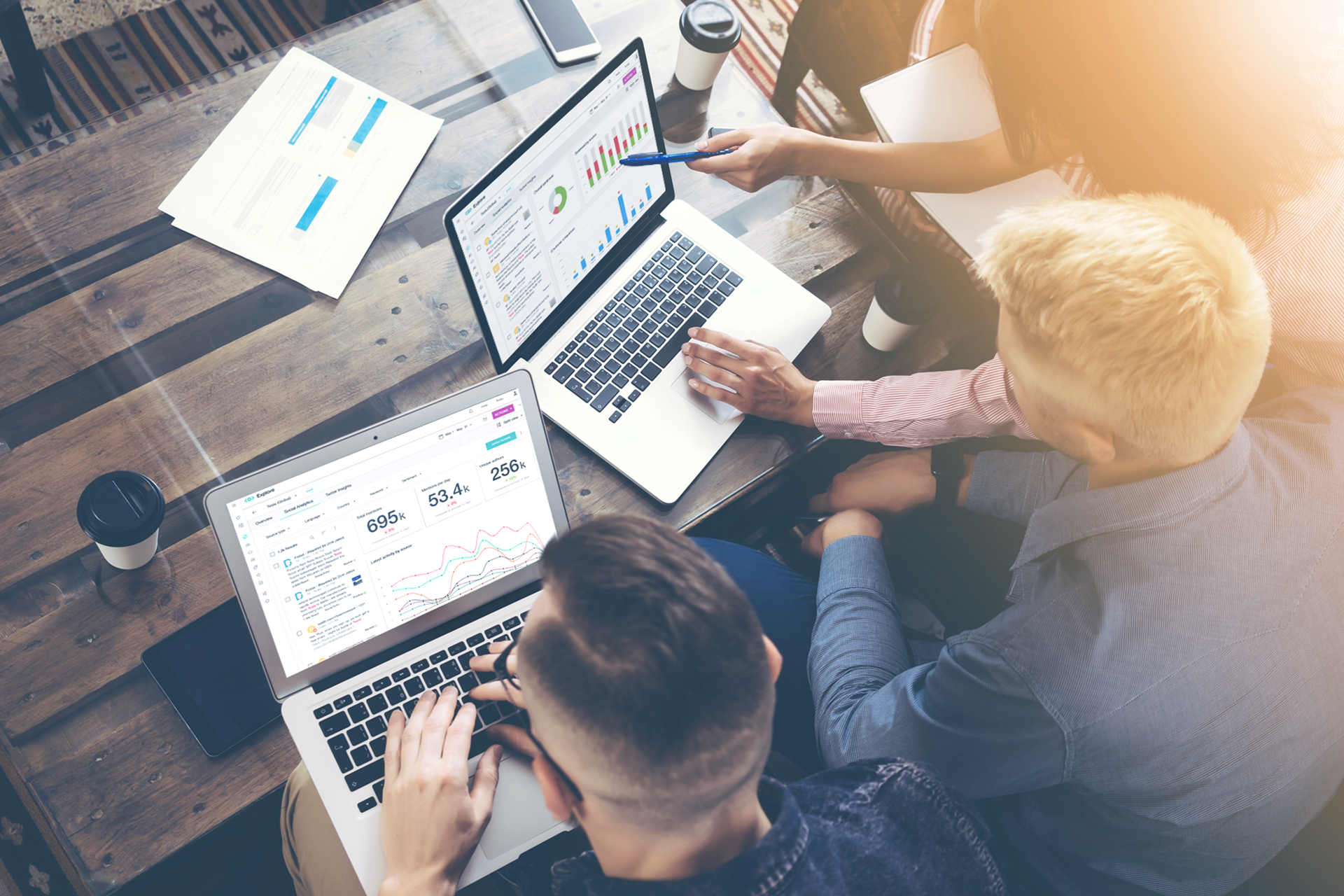 5 Collaboration Habits of Effective Marketers: A group of people sitting around a table on laptops.