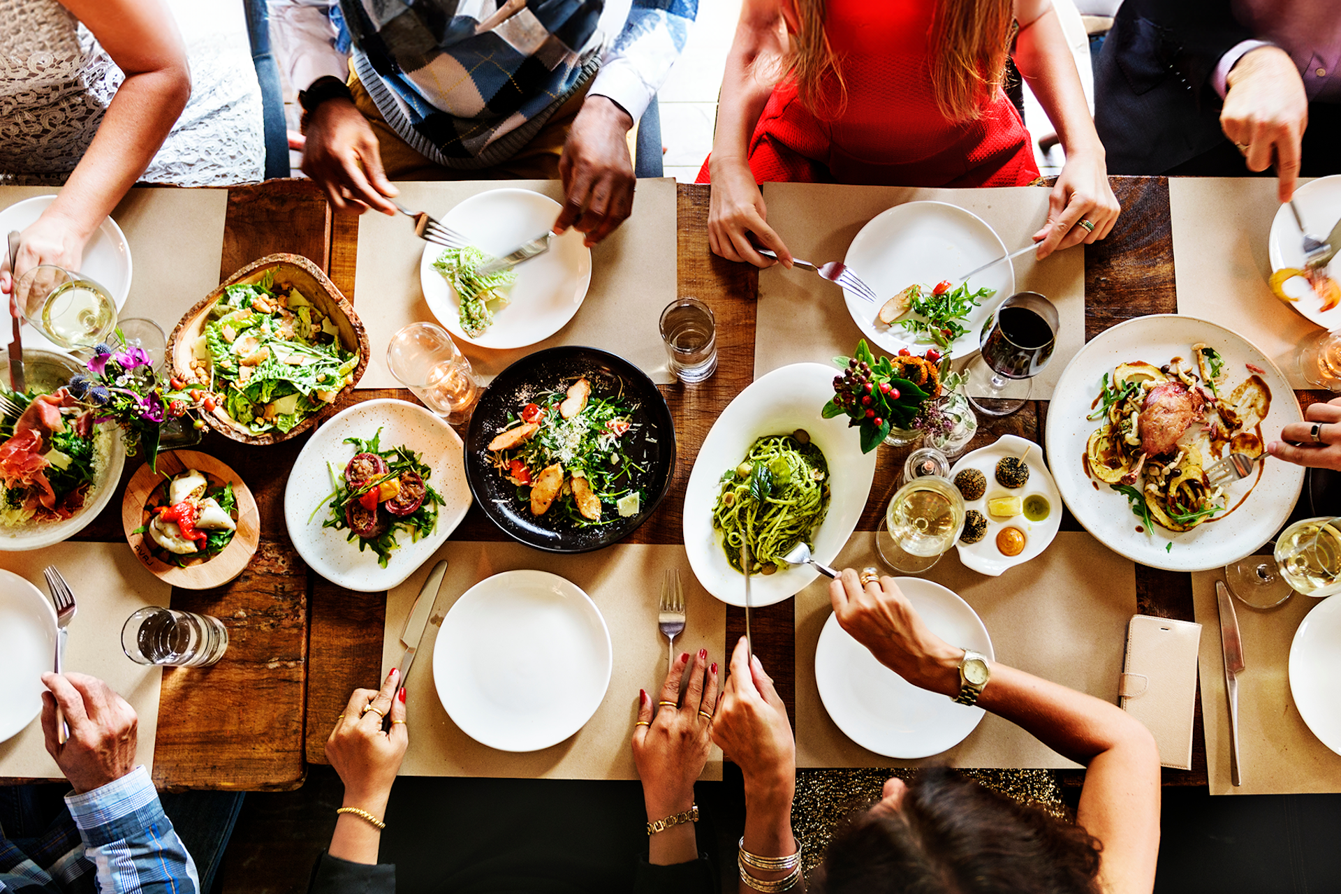 Des personnes assises à une table pleine d'assiettes de nourriture dans cette image pour le rapport 2024 Consumer Insights de Meltwater : Food & Beverage de Meltwater