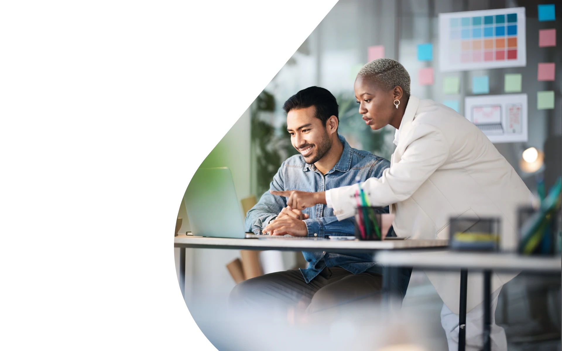 A man and woman looking at a laptop screen in an office. 