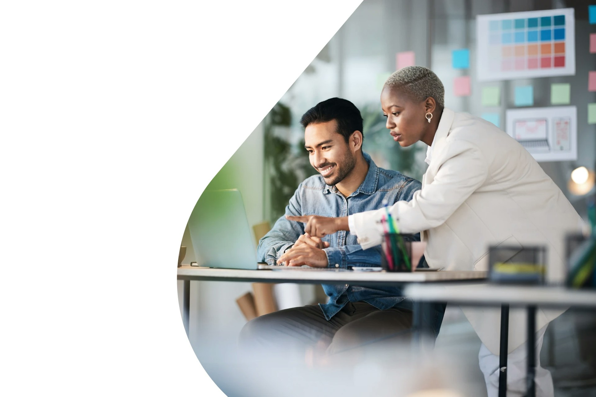 Ein Mann und eine Frau schauen in einem Büro auf einen Laptop-Bildschirm.