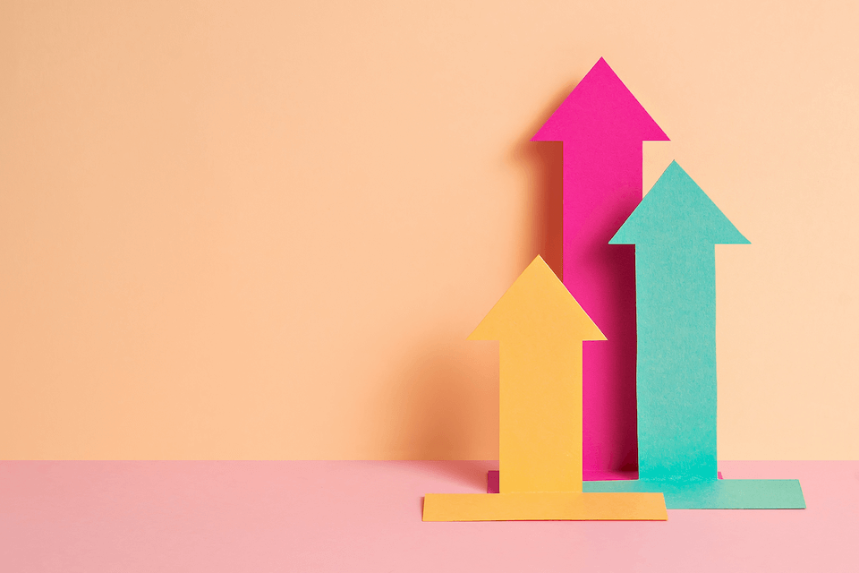 Three colorful arrows cut out of paper pointed upwards. The arrows are meant to reflect the direction of a graph that you might find after creating a PR or marketing report.