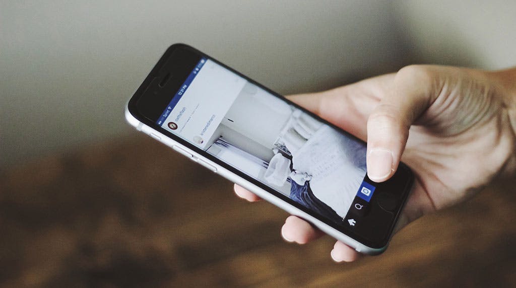 hand on mobile phone scrolling through instagram