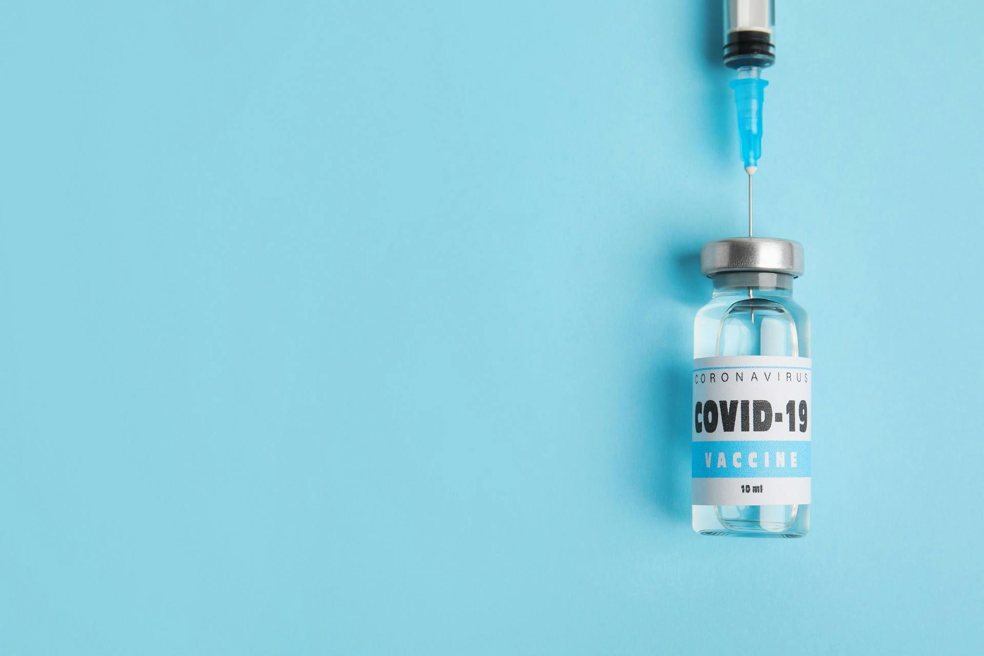 COVID vaccine vial and syringe on blue background