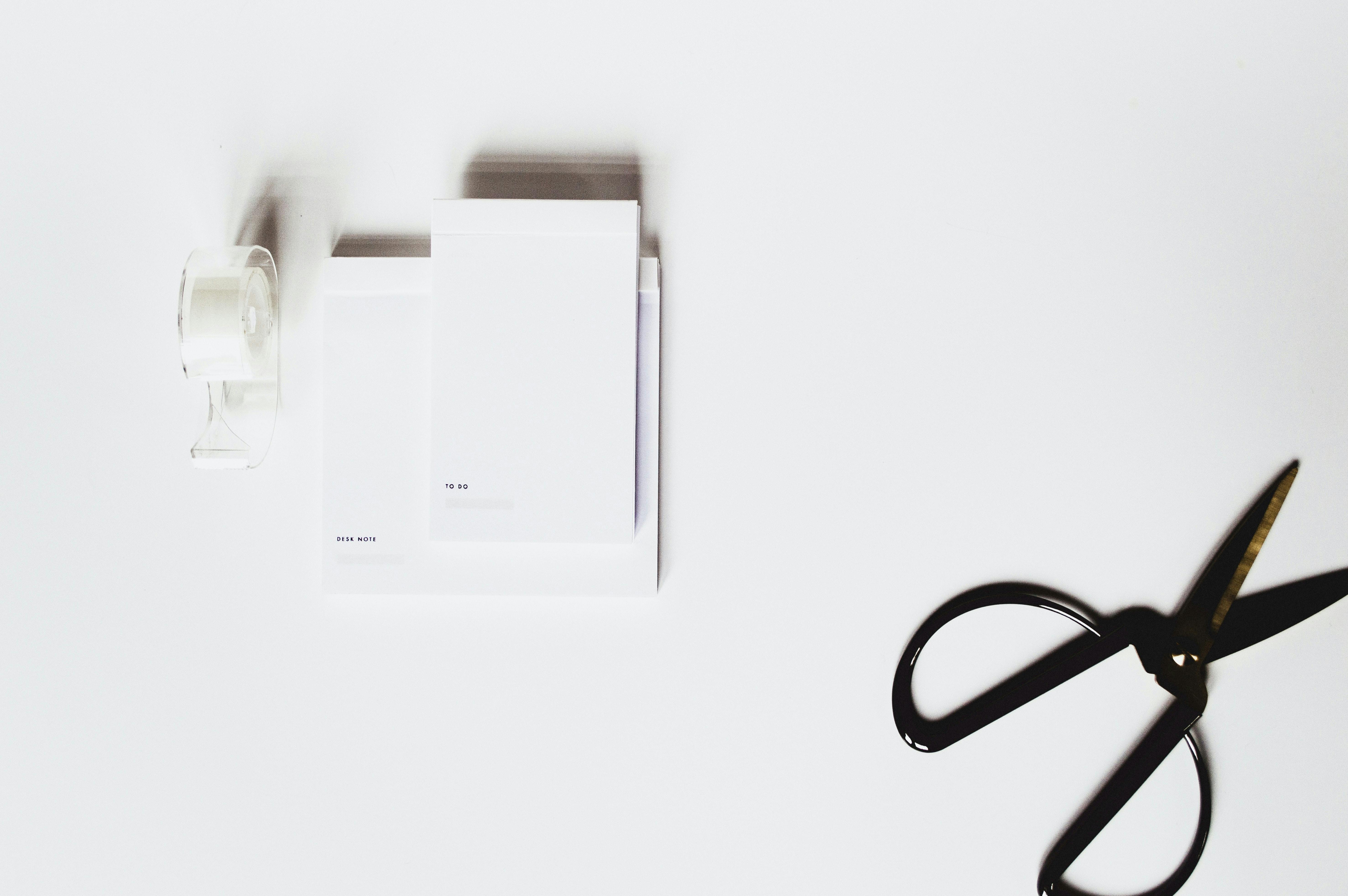 Black scissors on white table with different sizes of paper. Editing and cutting your video is important for a polished look.