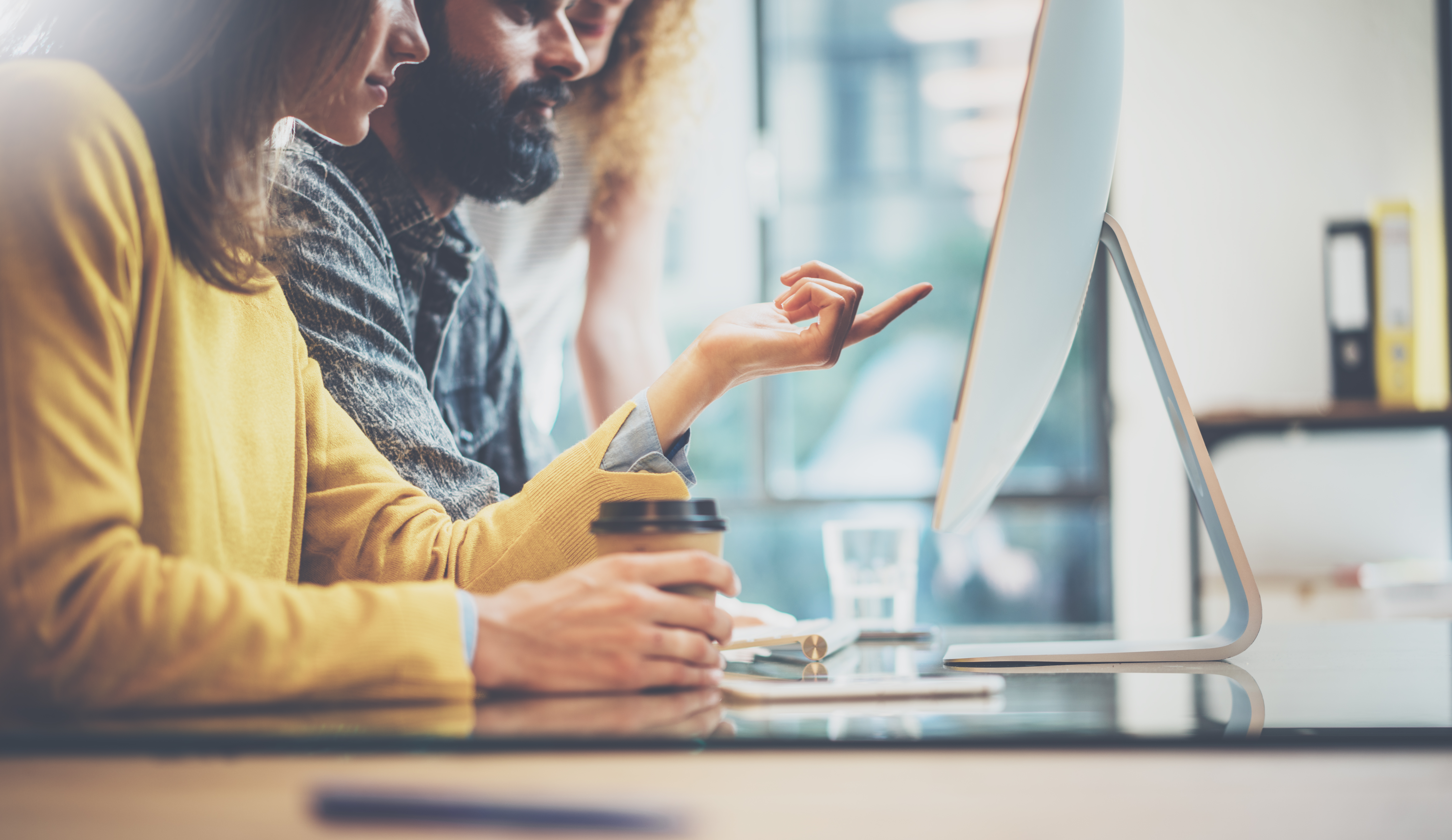 Coworkers looking and pointing at a laptop on a desk