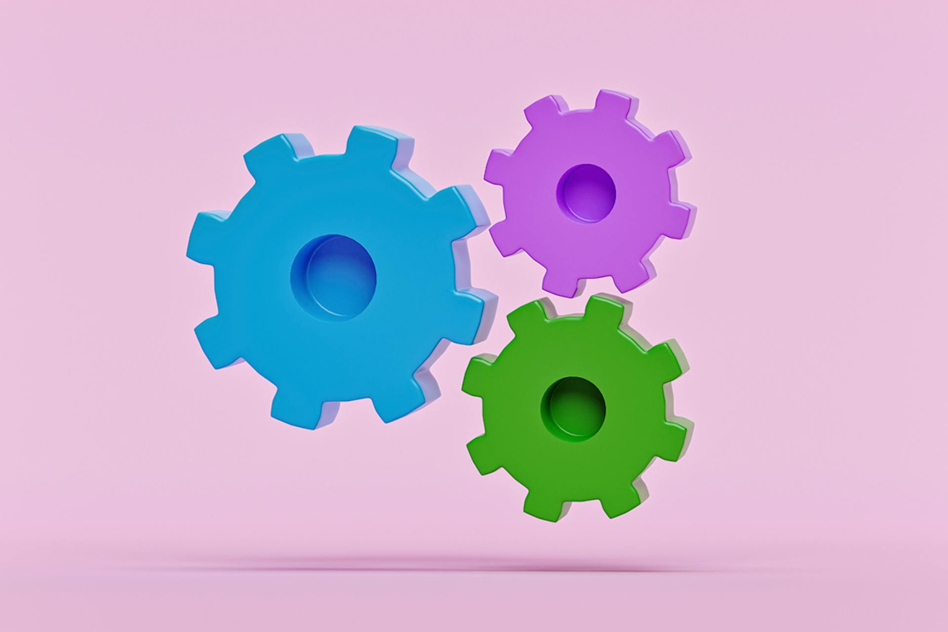 Green, blue, and purple gears float against a pink background in this image for a blog about marketing automation.