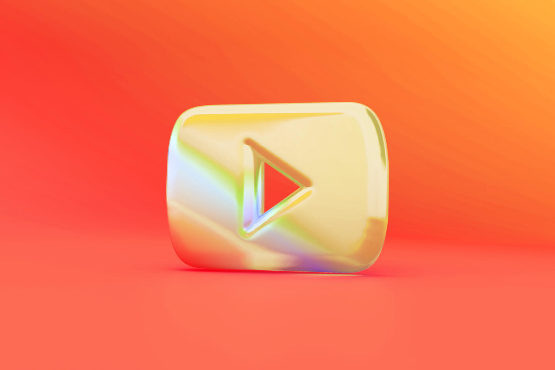 Ein glänzendes, goldenes 3D-YouTube-Logo auf einem leuchtend orangefarbenen Hintergrund.
