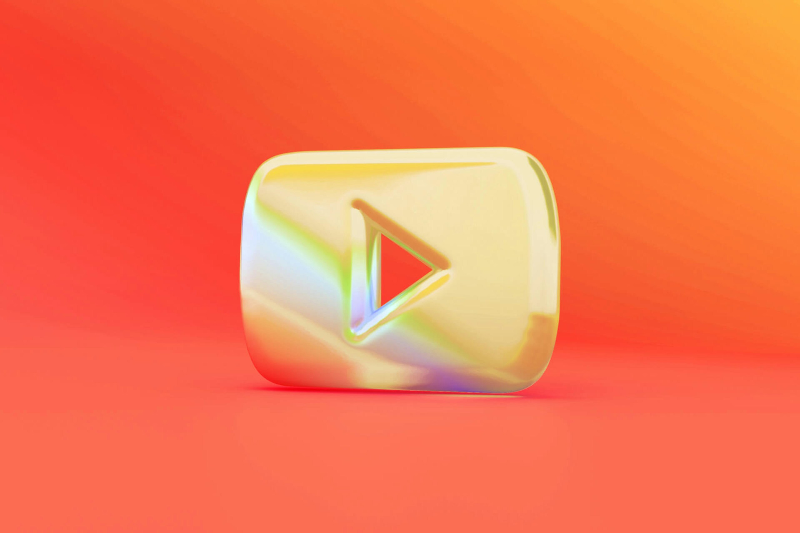 Ein glänzendes, goldenes 3D-YouTube-Logo auf einem leuchtend orangefarbenen Hintergrund.