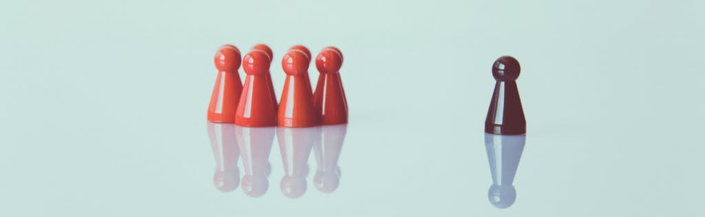 Acht rote Spielfiguren und eine abseits stehende schwarze Figur symbolisieren die Zielgruppensegmentierung im Marketing.