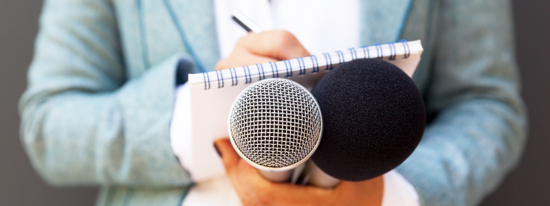 Photo of someone taking notes while holding two microphones