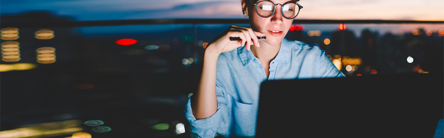 woman with glasses working in front of laptop
