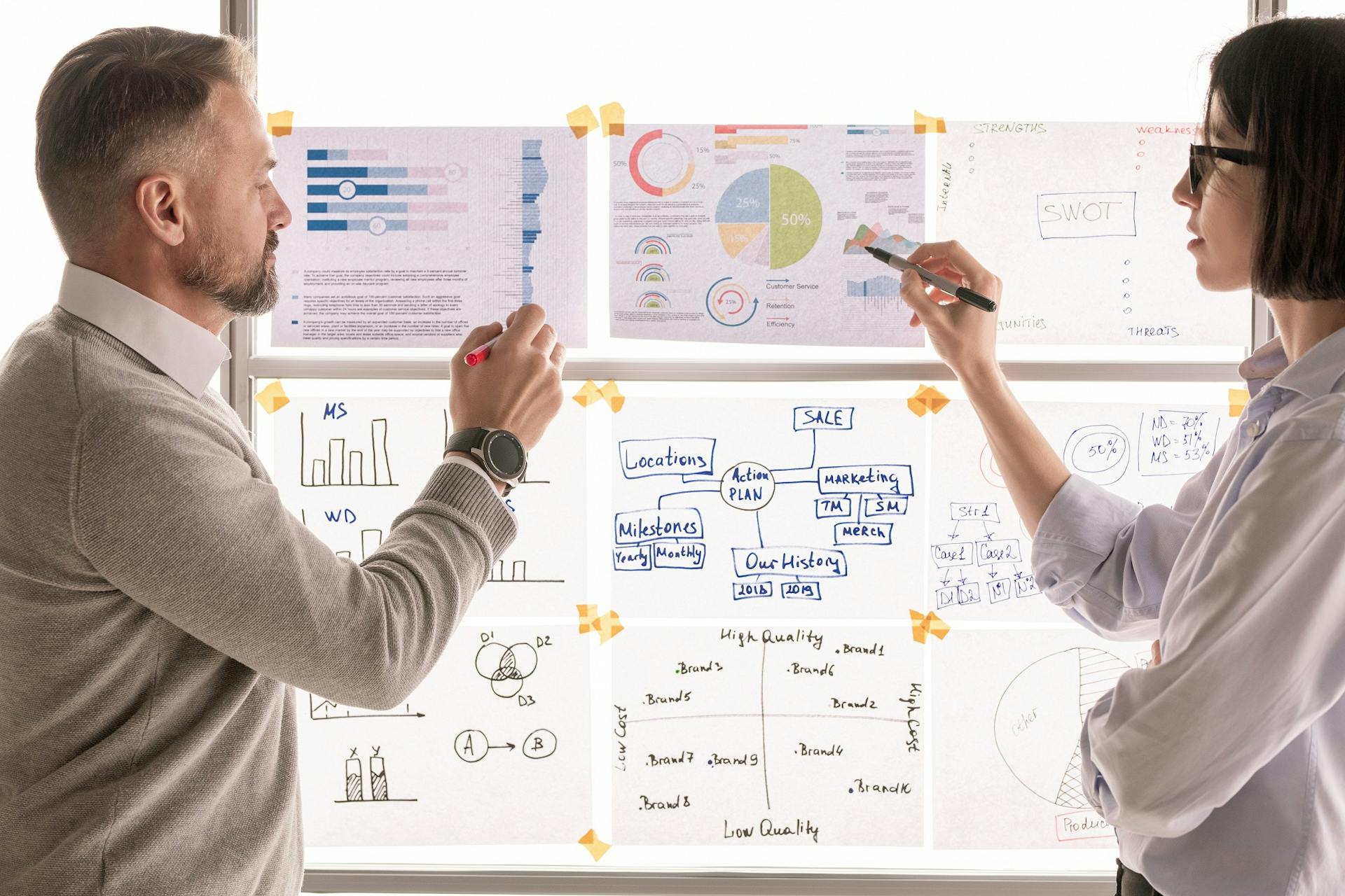 Two people standing in front of a board brainstorming