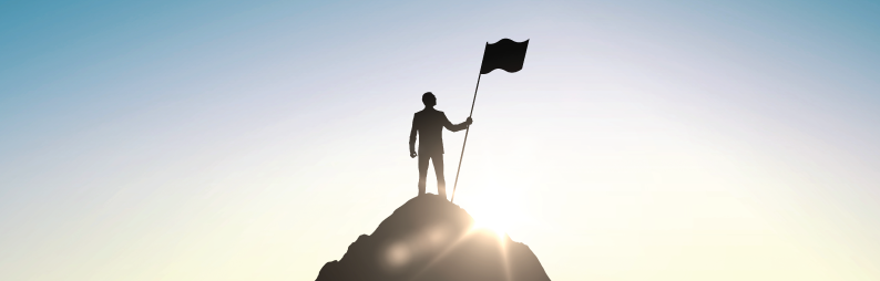 Photo of a man at a mountain top holding a flag