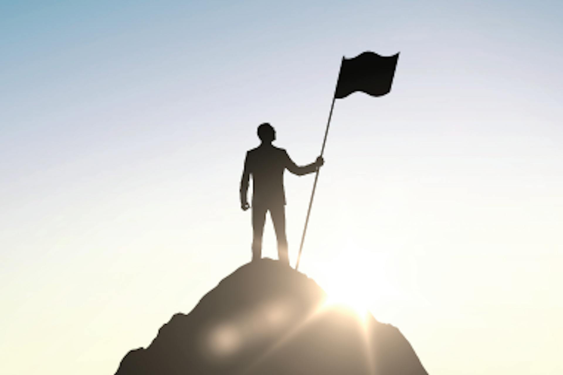 Photo of a man at a mountain top holding a flag
