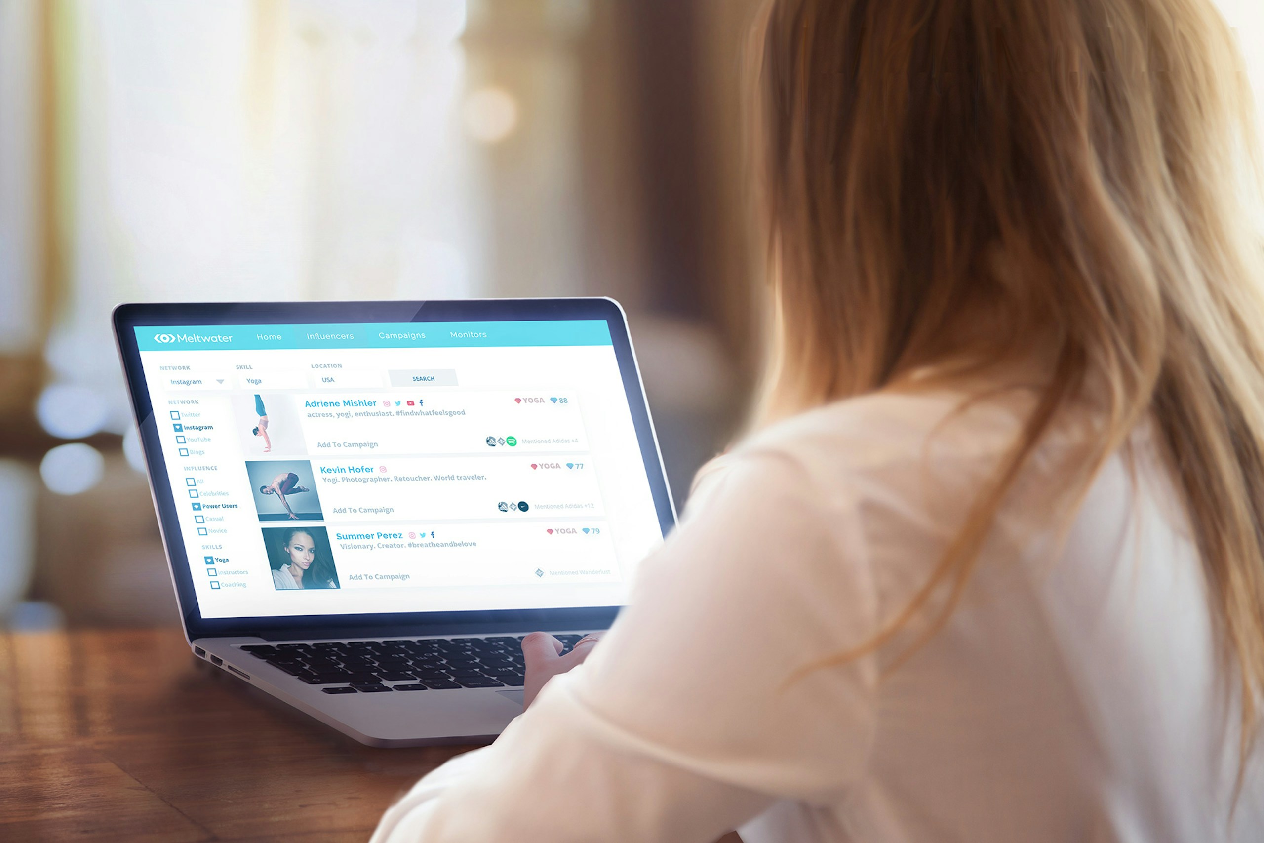 Photo of a woman sitting in front of her laptop with the Meltwater Media Intelligence Platform opened