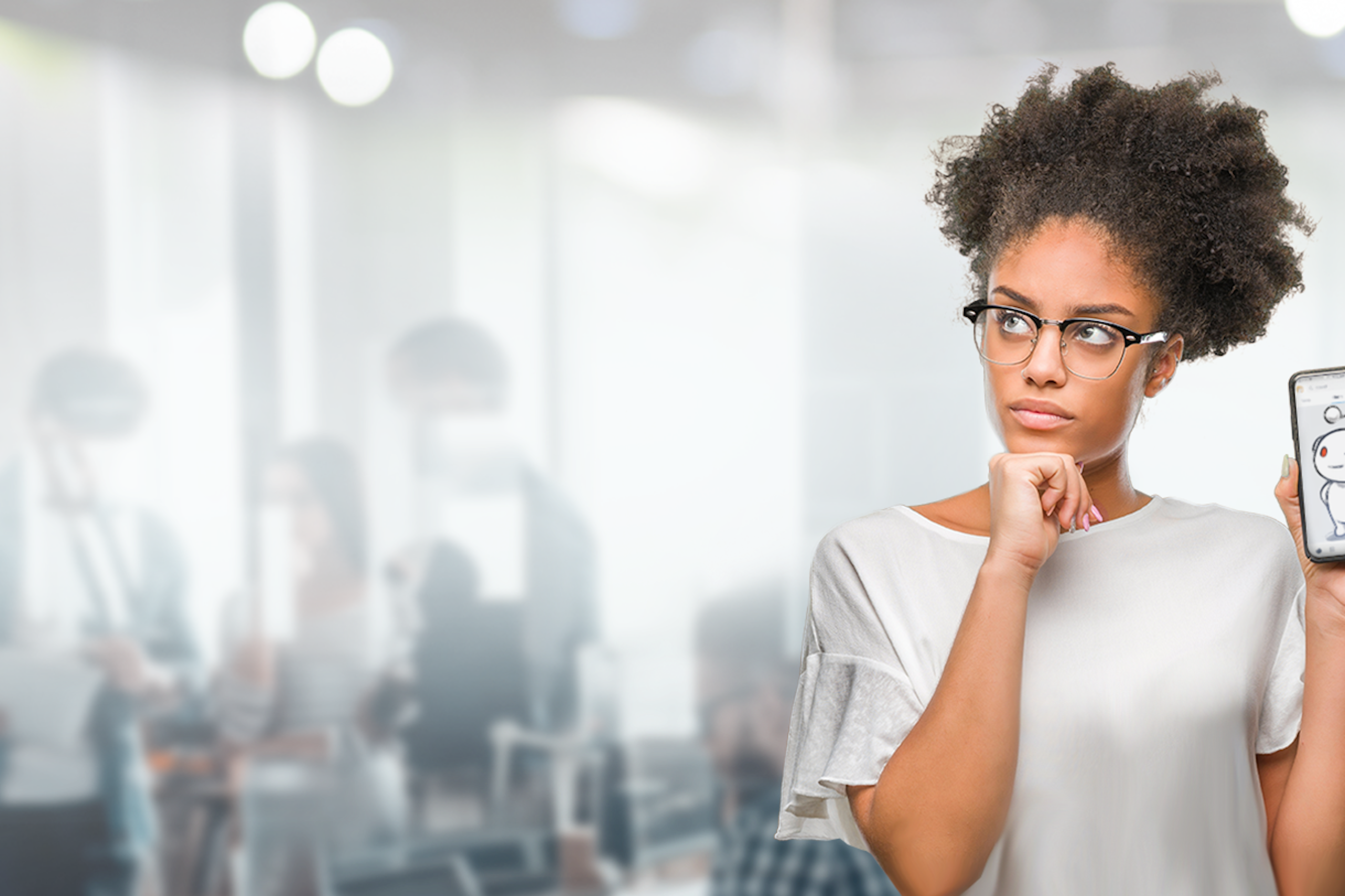 A woman in an office holding up a smart phone with a quizzical look on her face