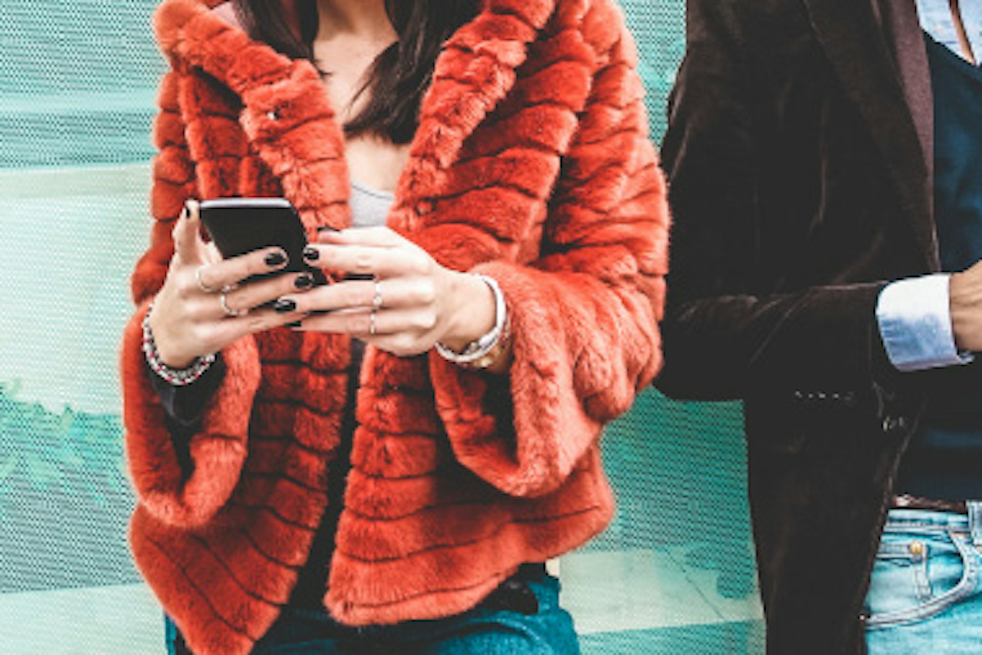 two people in fashion clothing holding mobile phones