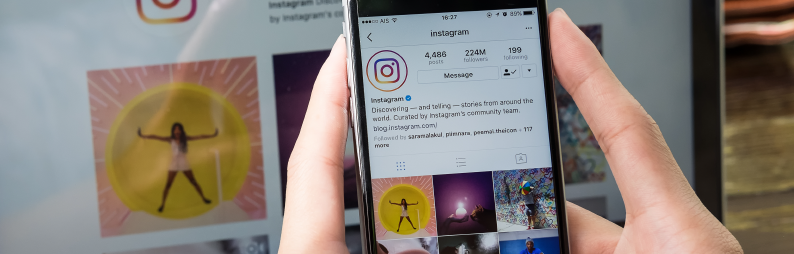 A hand holding a phone with the Instagram app open 