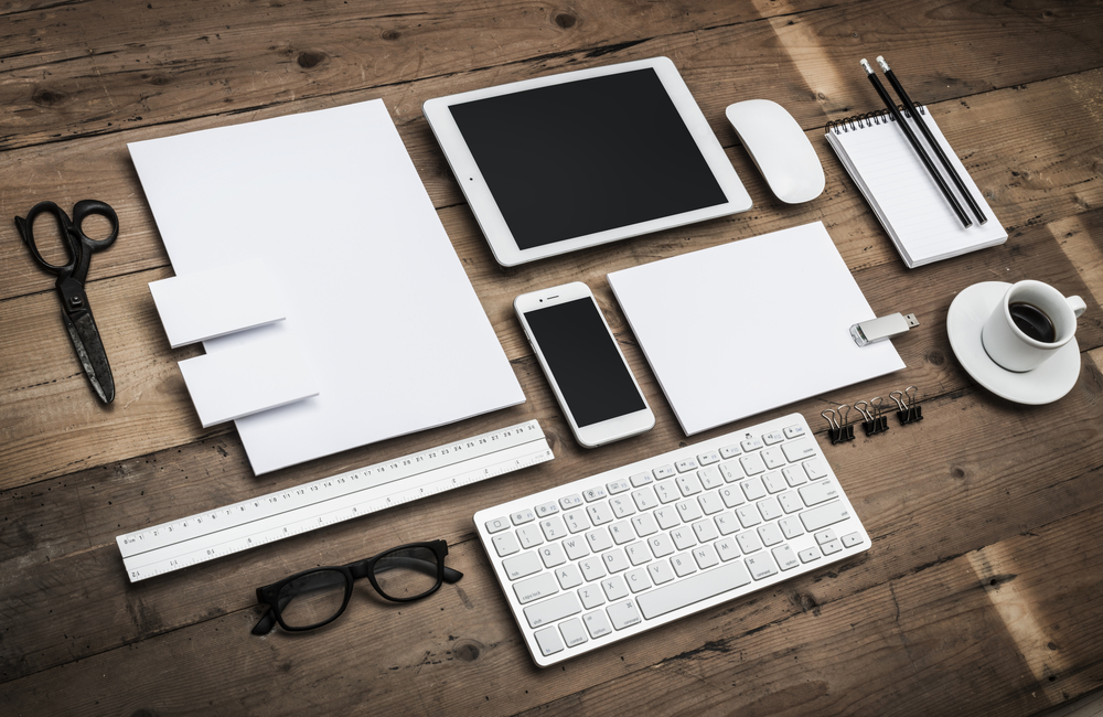 Man sieht ein Foto eines Holztisches mit ungebrandeten, weißen Utensilien darauf. Das Foto ist das Titelbild unseres Beitrags zur Erstellung einer Corporate Identity.