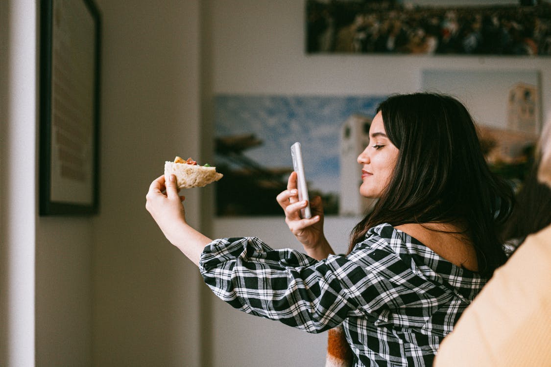 Young woman taking picture of food food blogging
