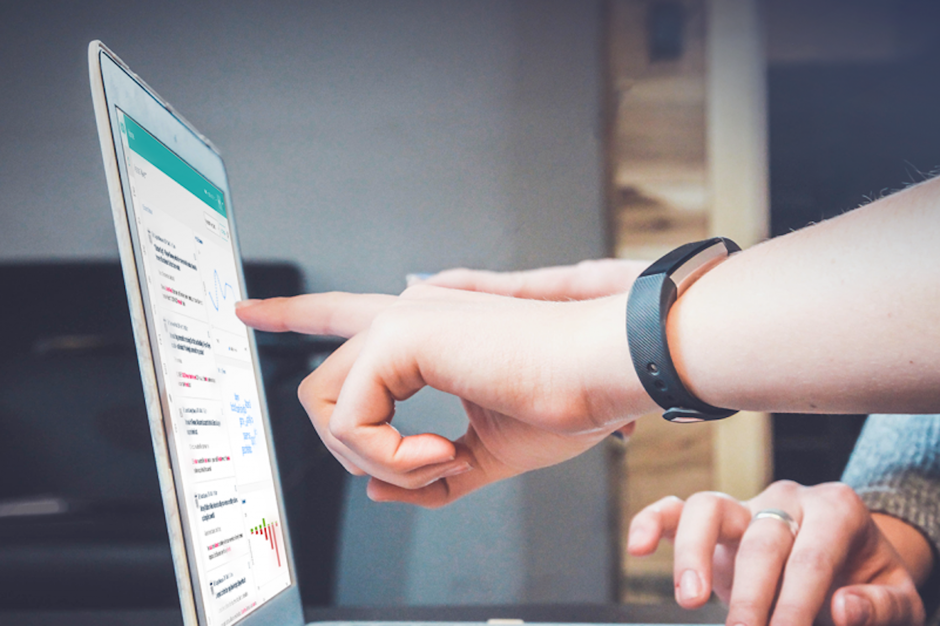 Photo of people pointing at a screen with the Meltwater Media Intelligence Platform on it