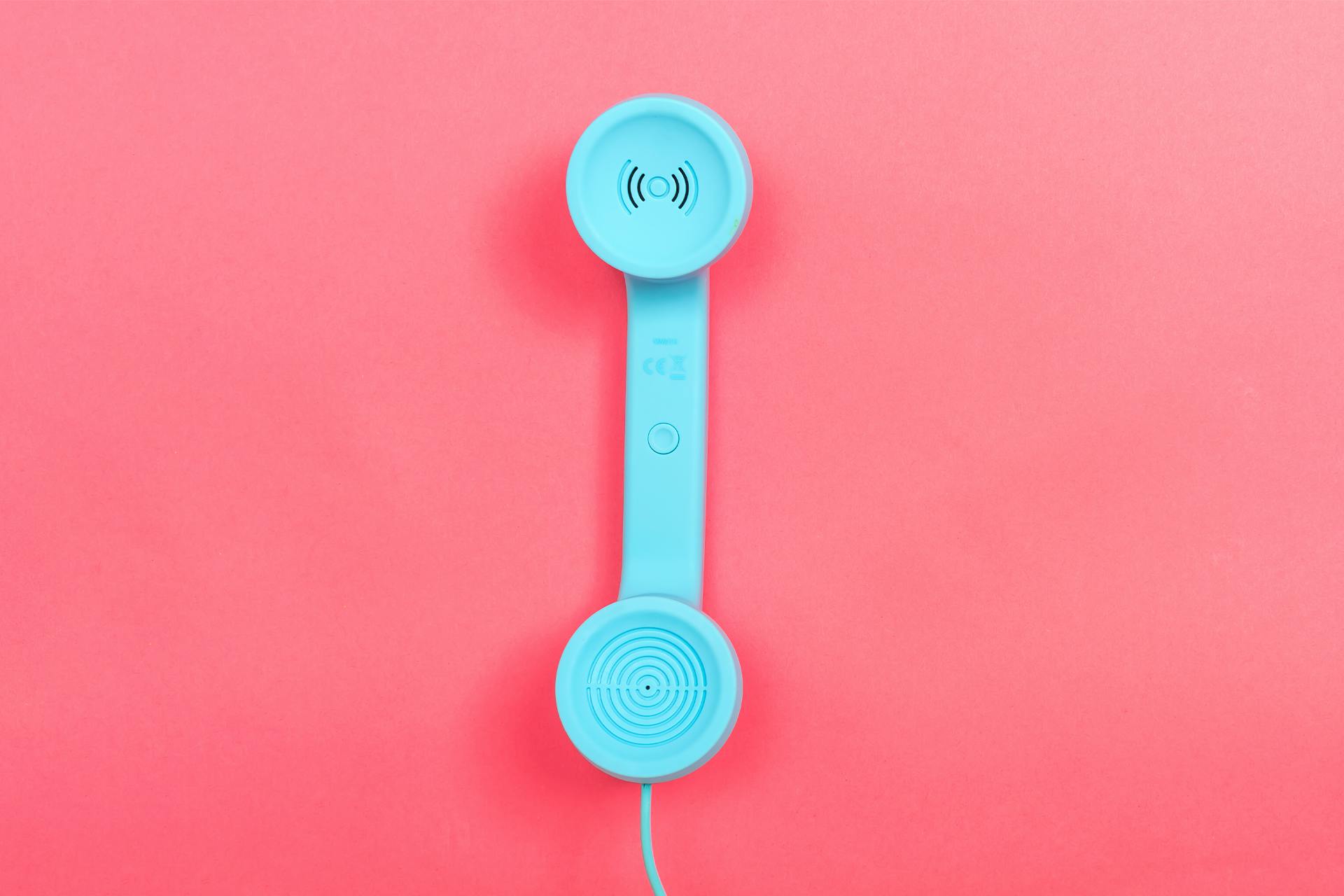 A blue phone, which you may use to call a friend to engage in referral marketing by calling a friend to tell them about a product or service, set against a red background. 