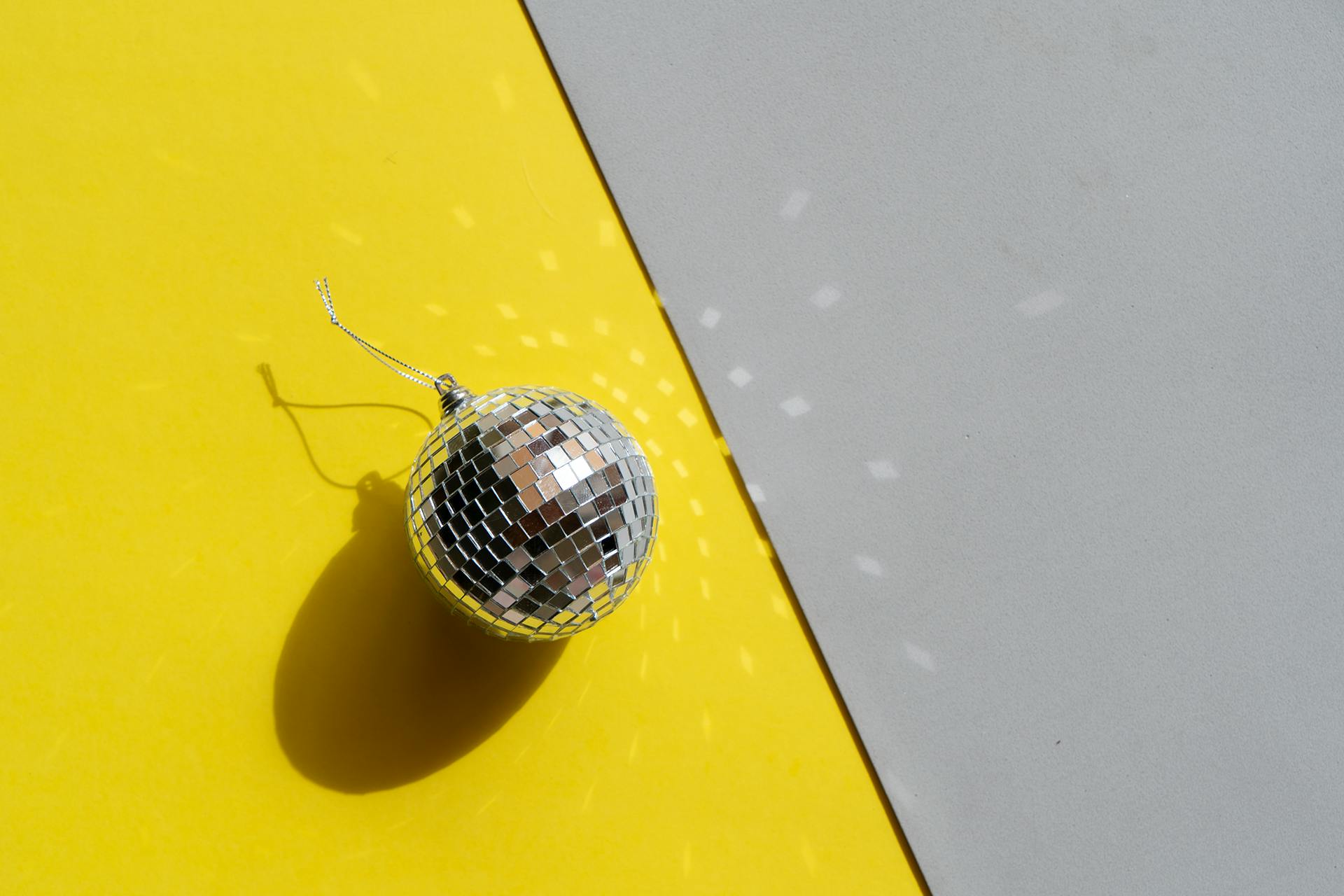 Mini disco ball on yellow and grey background