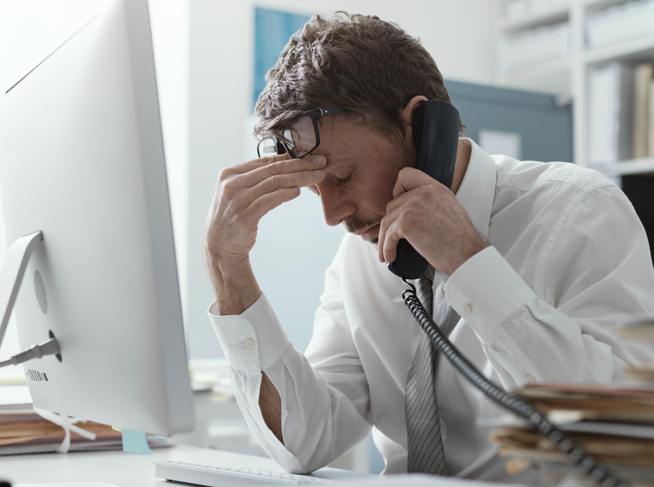 A man using a landline telephone at his work desk