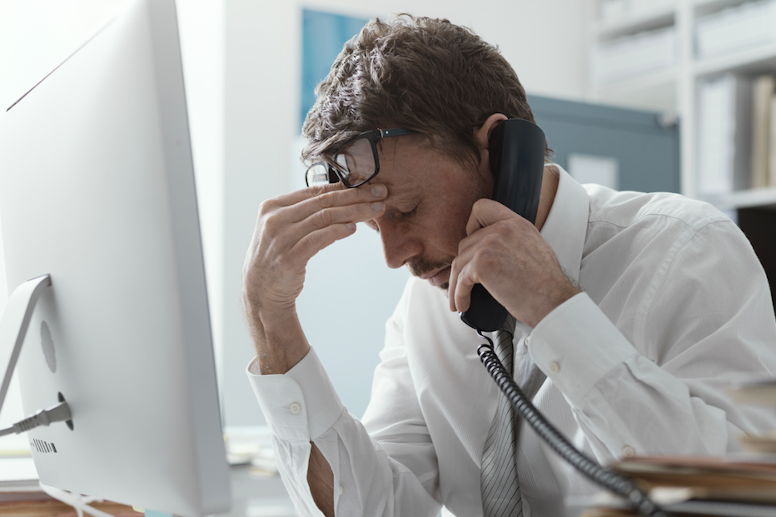 A man using a landline telephone at his work desk