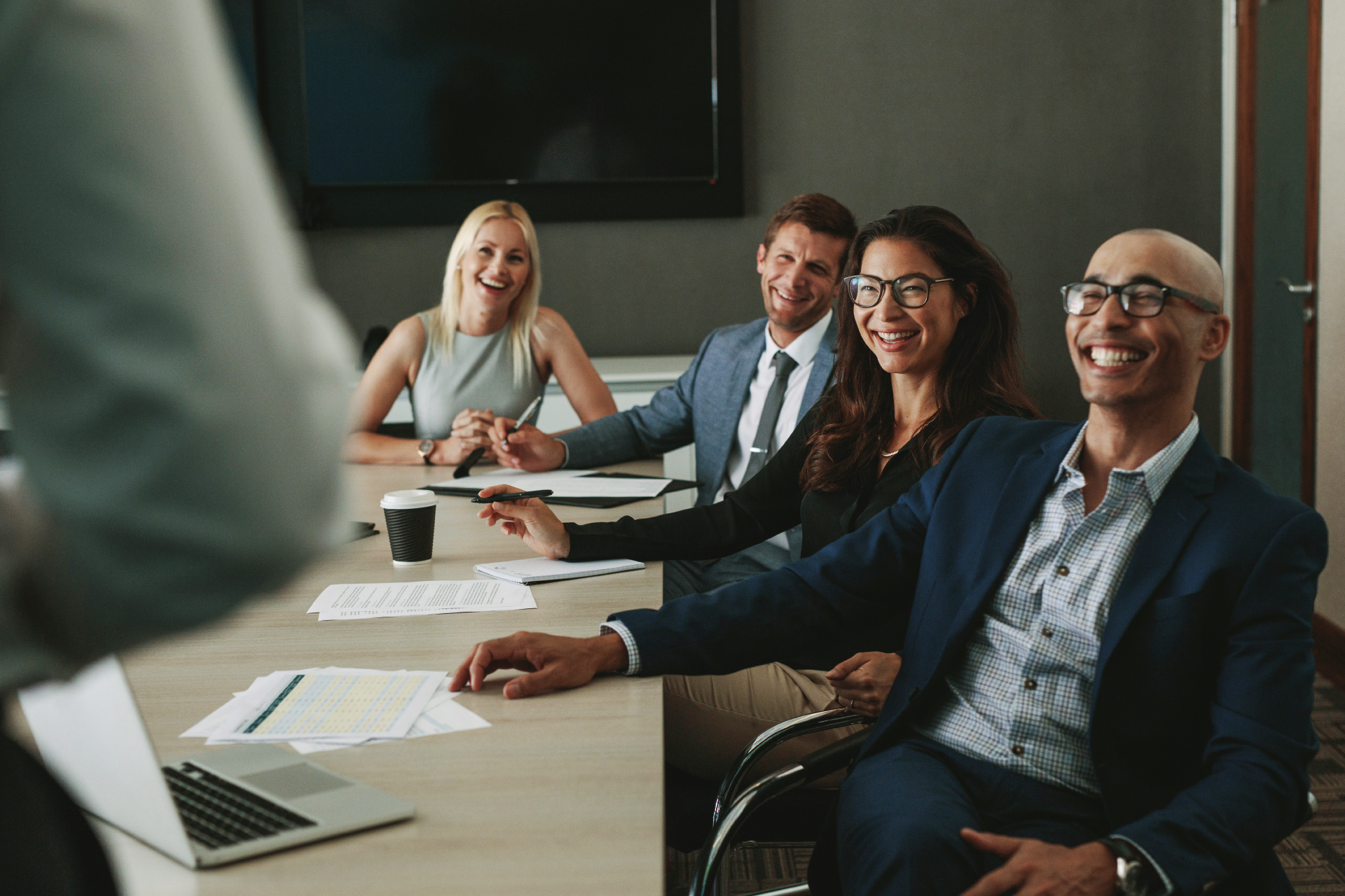 People sitting around a boardroom table laughing 