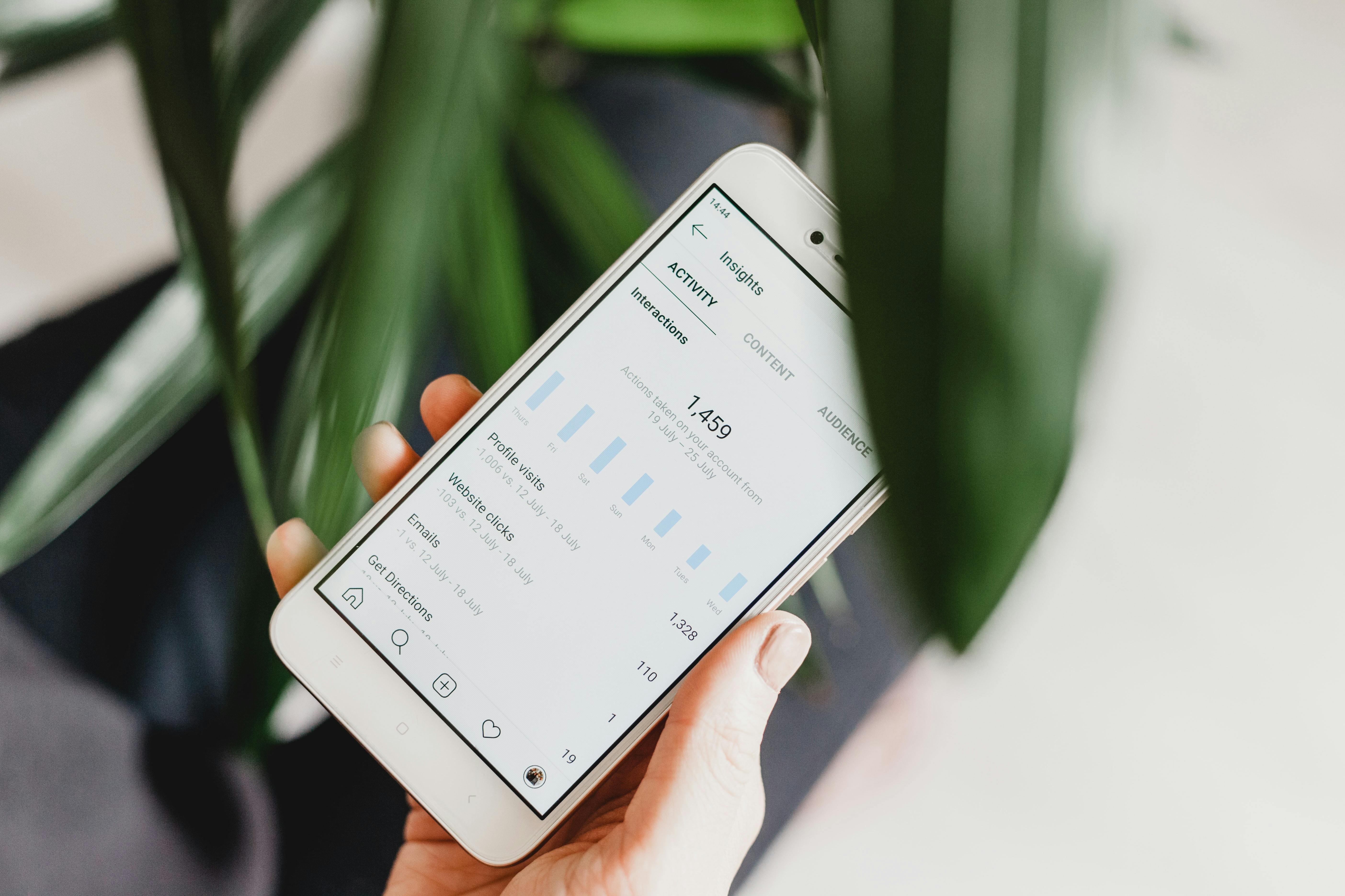 Person holding a phone showing Instagram analytics on a business profile.