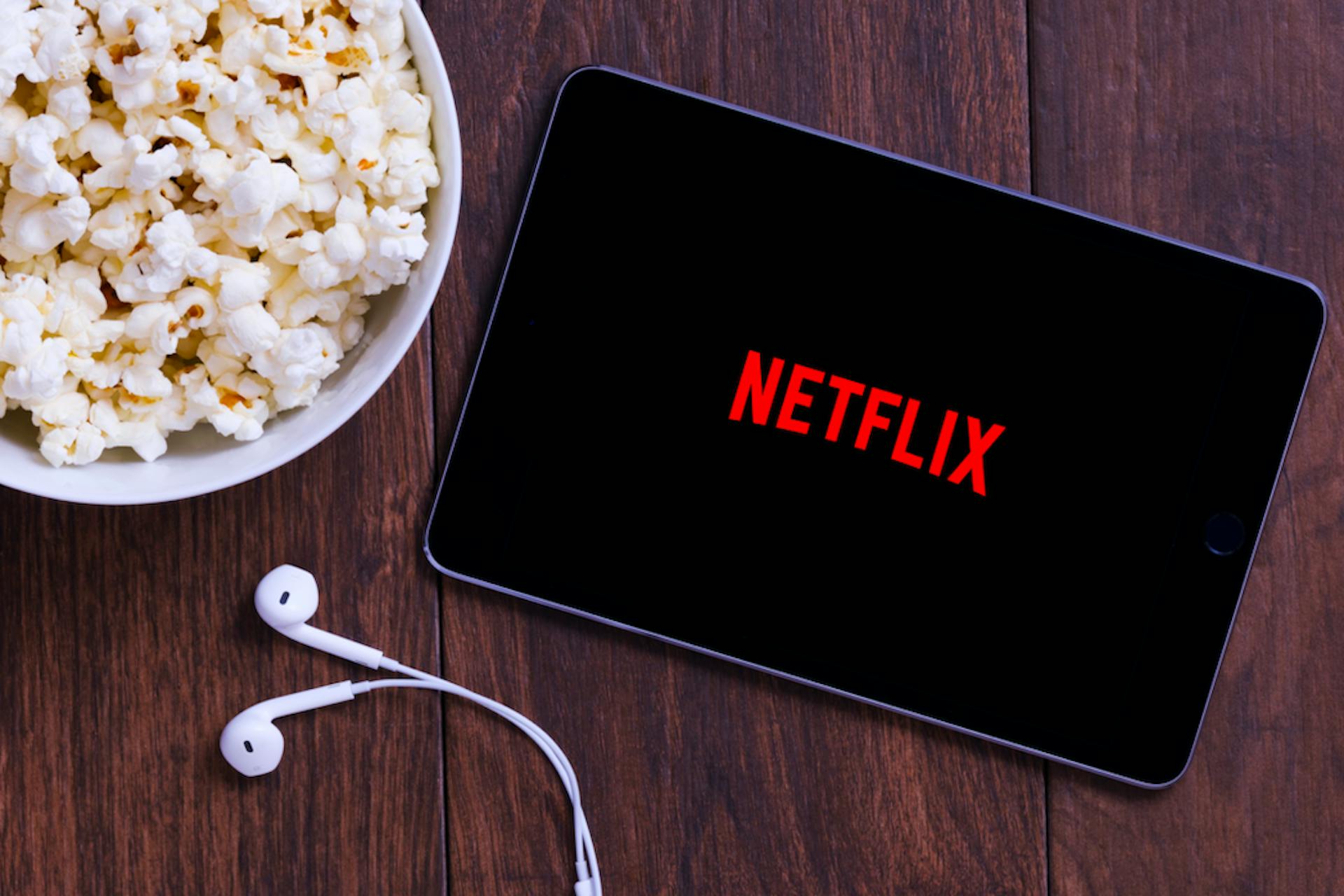 image of an ipad with the netflix app open next to a bowl of popcorn 