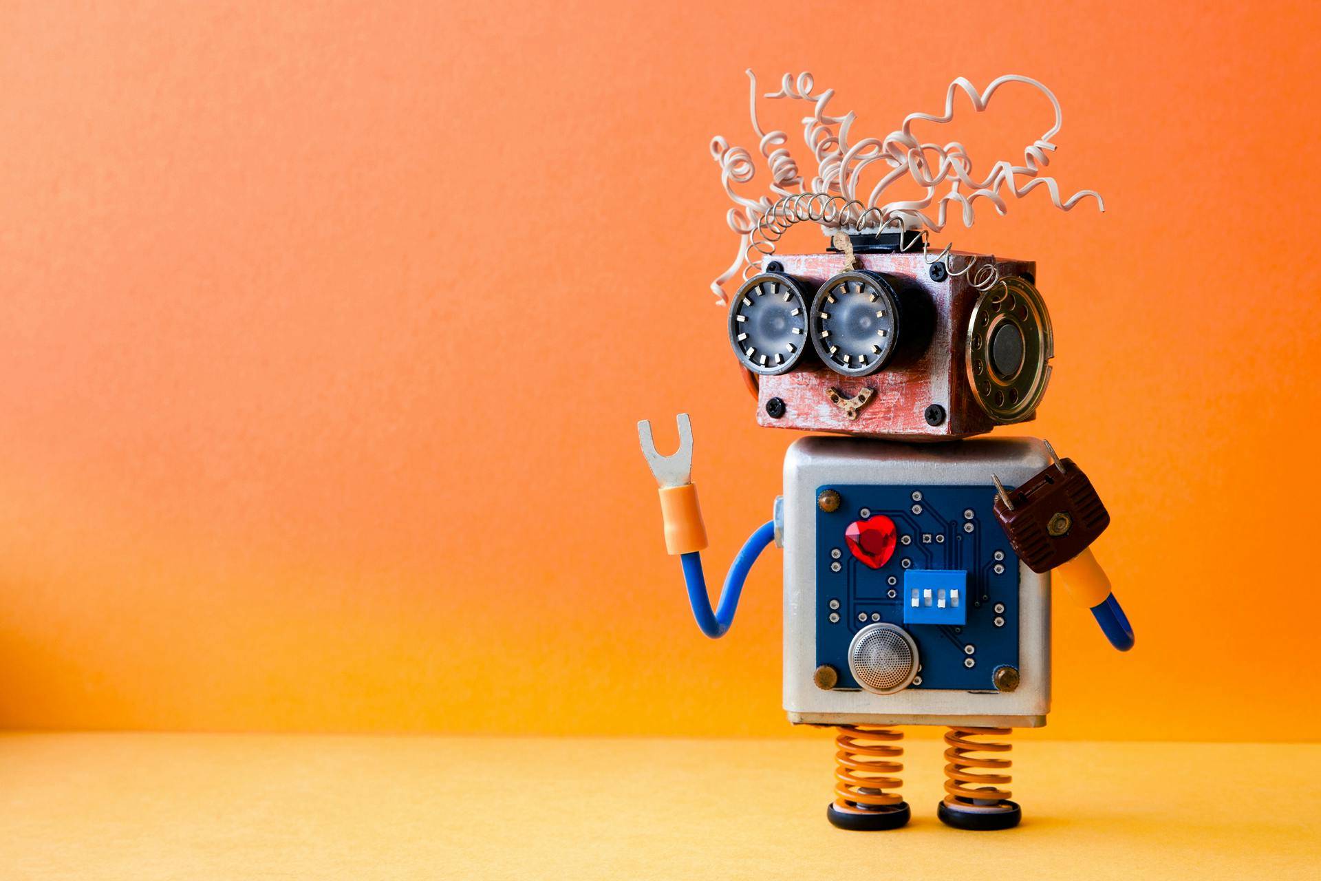 A toy robot that has been made using scraps of pieces from different machines or mechanical parts, like springs, electrical plugs, and wires. He could be social-savvy bot answering questions around how to build similar social media bots.