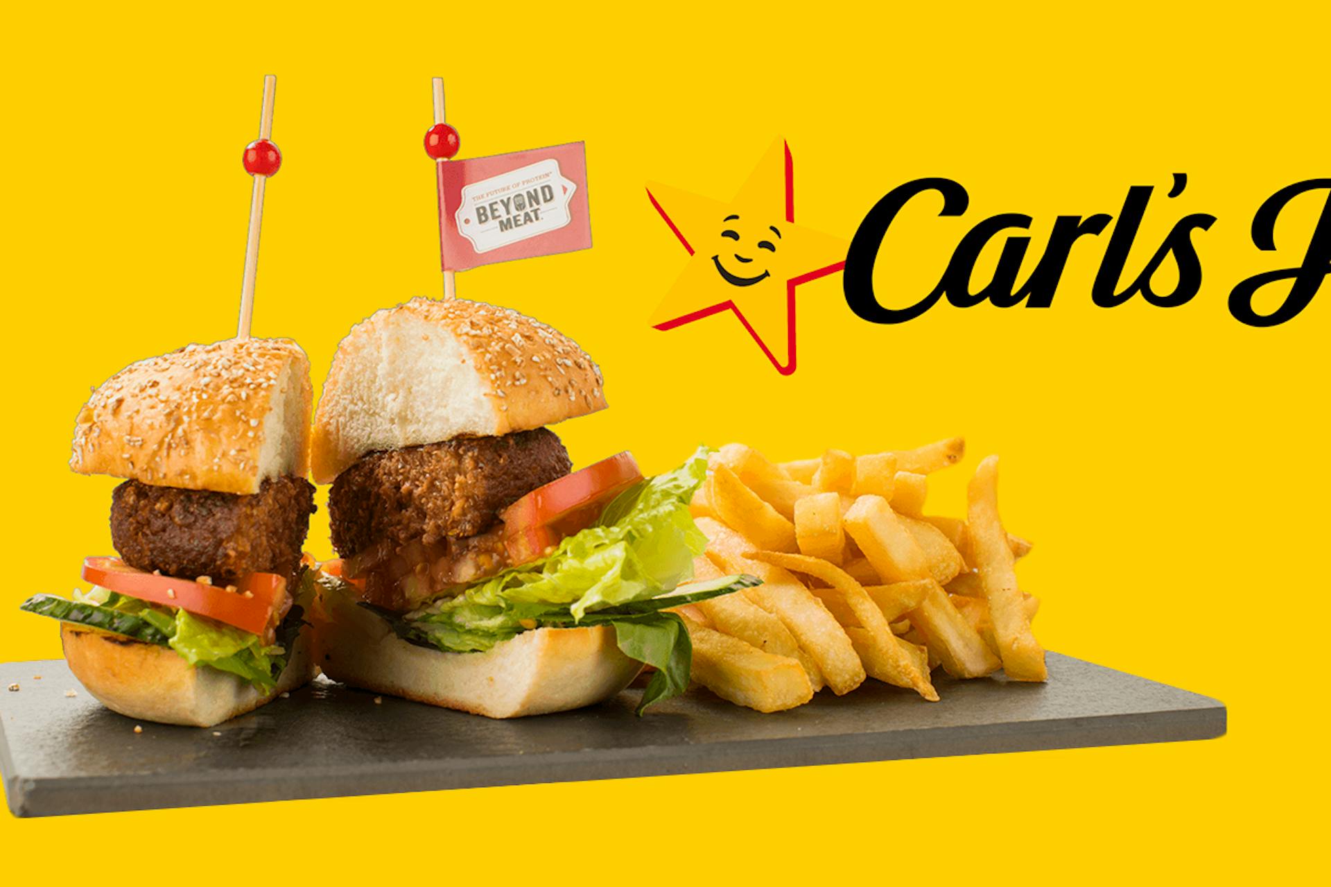 Fresh burger, cut in half, hot chips on a flat board. Carl's JR. logo o a yellow background. 
