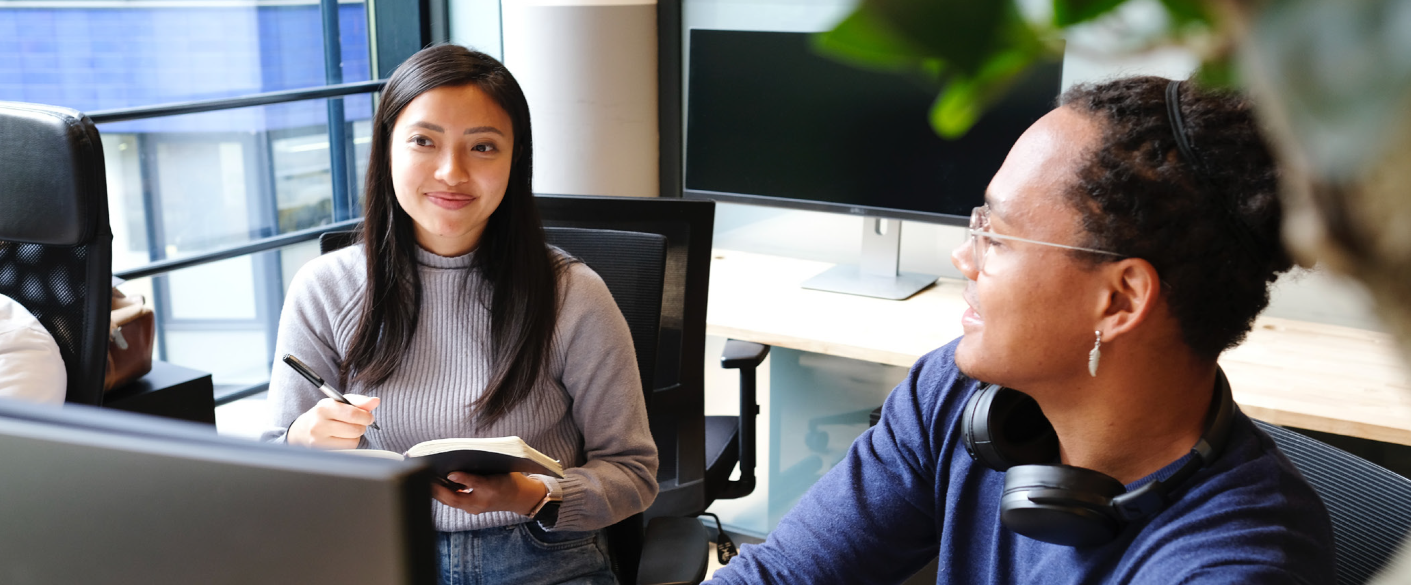 Two women sitting in an office conference room and smiling. Guide to Global Brand Management
