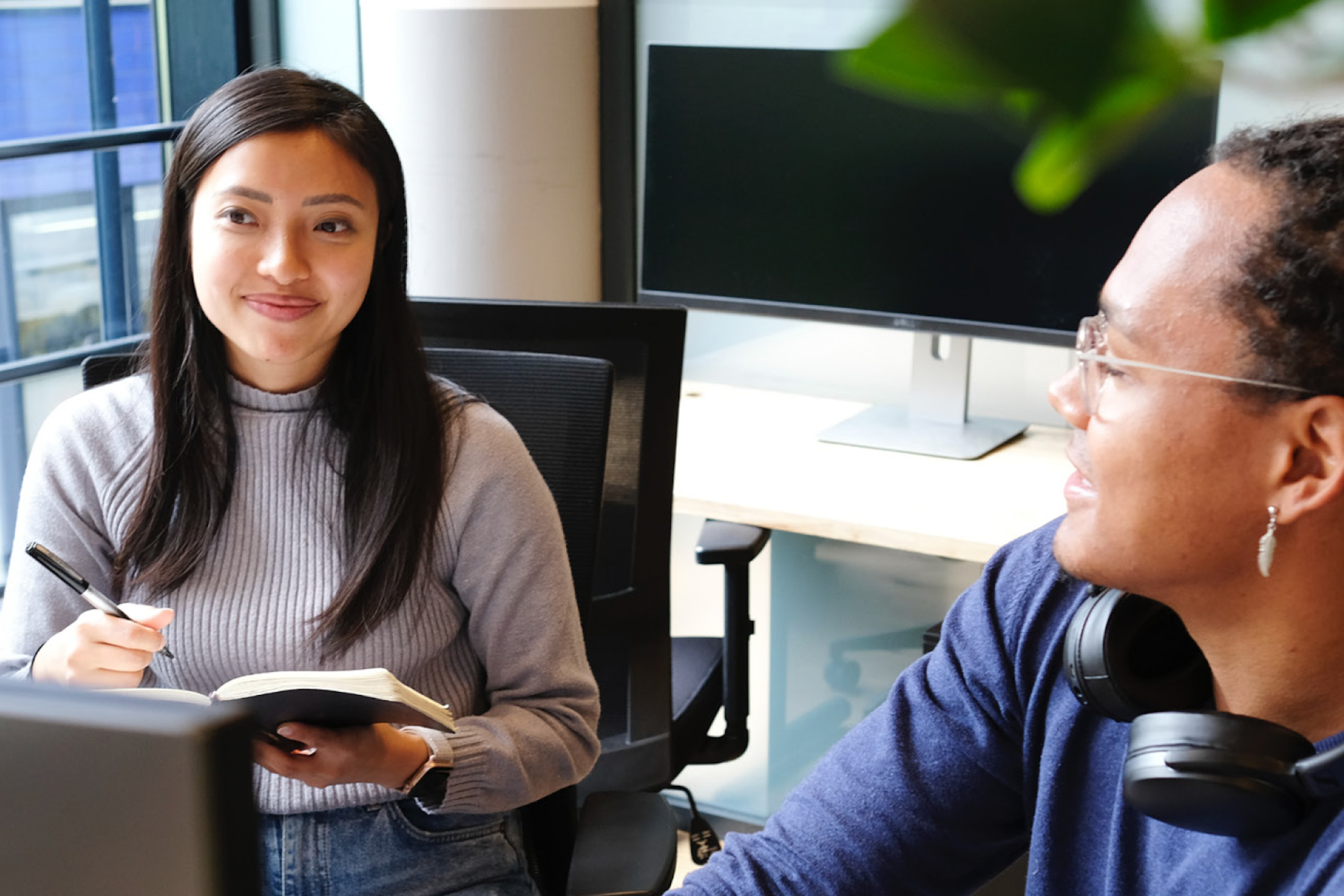 Two women sitting in an office conference room and smiling. Guide to Global Brand Management