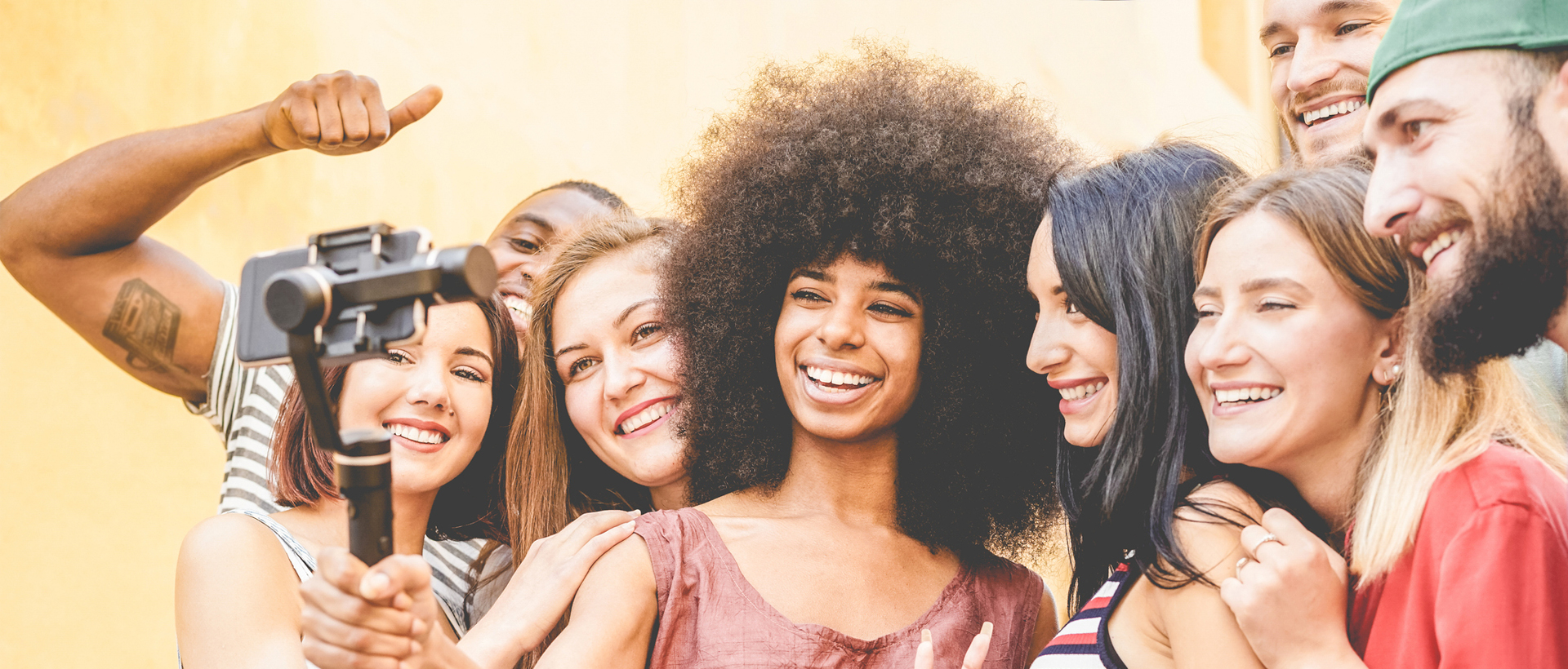 A diverse group of young influencers looking at a smart phone, filming a campaign.