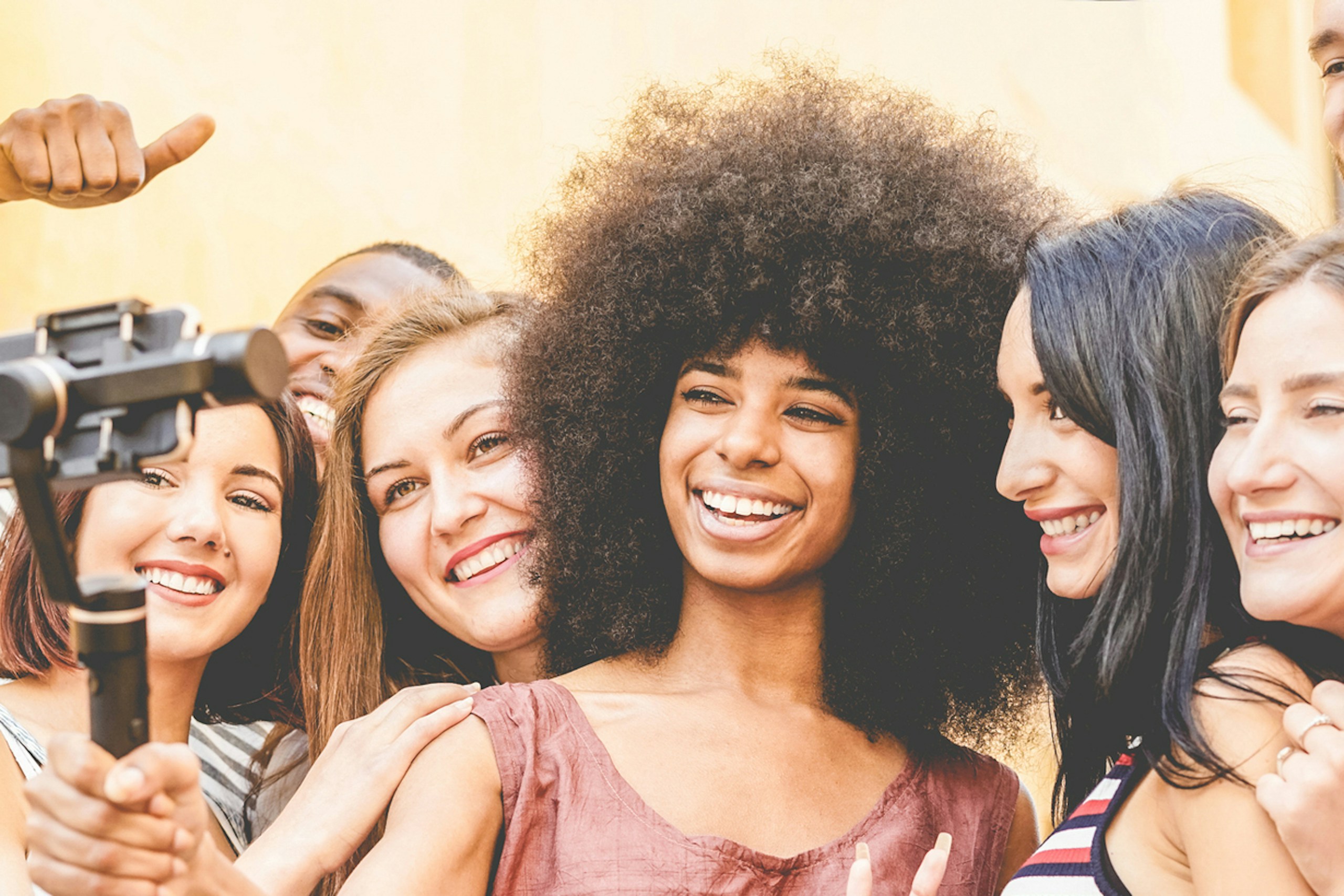 A diverse group of young influencers looking at a smart phone, filming a campaign.