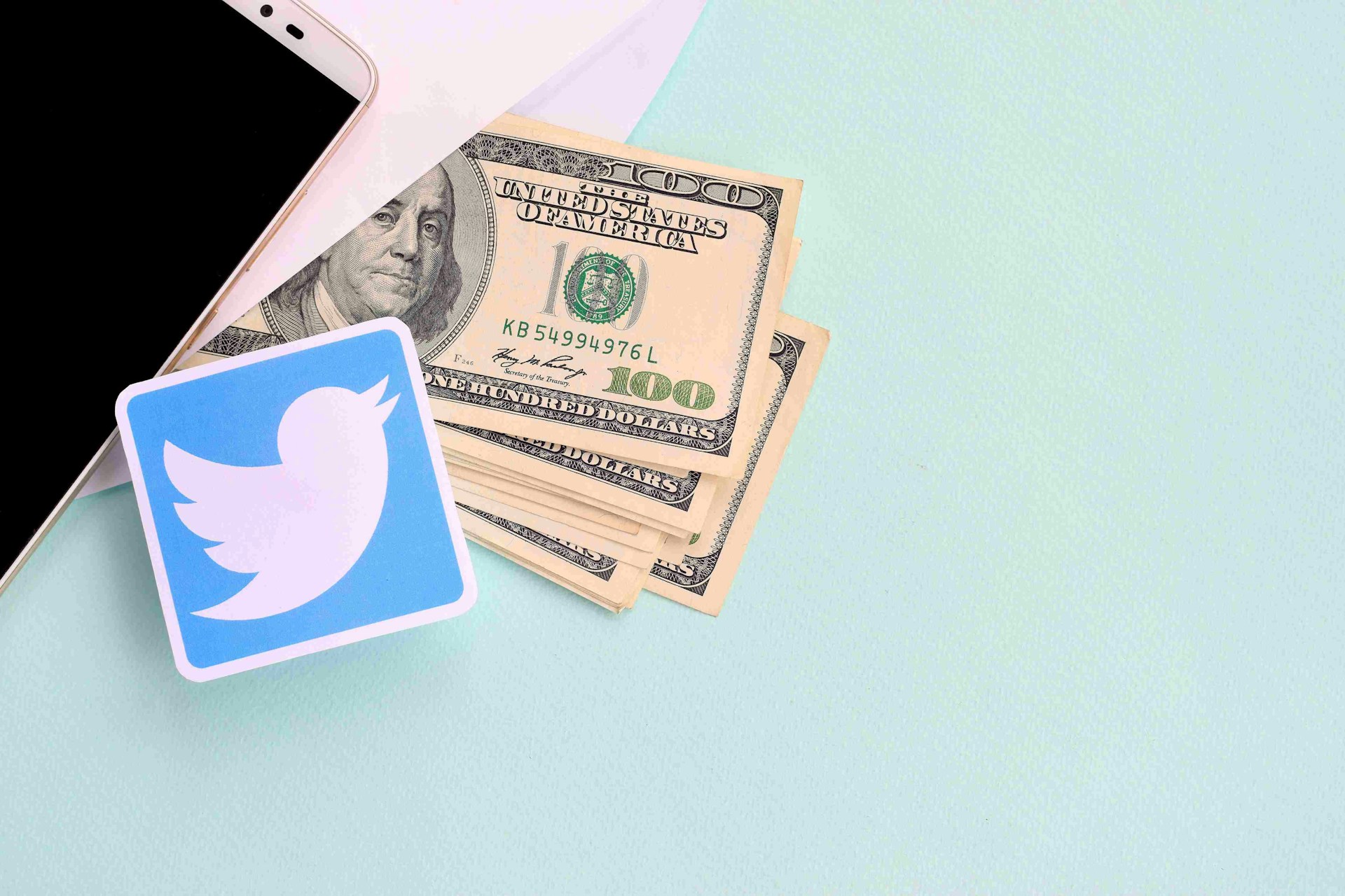 twitter logo with stack of dollar bills and smartphone