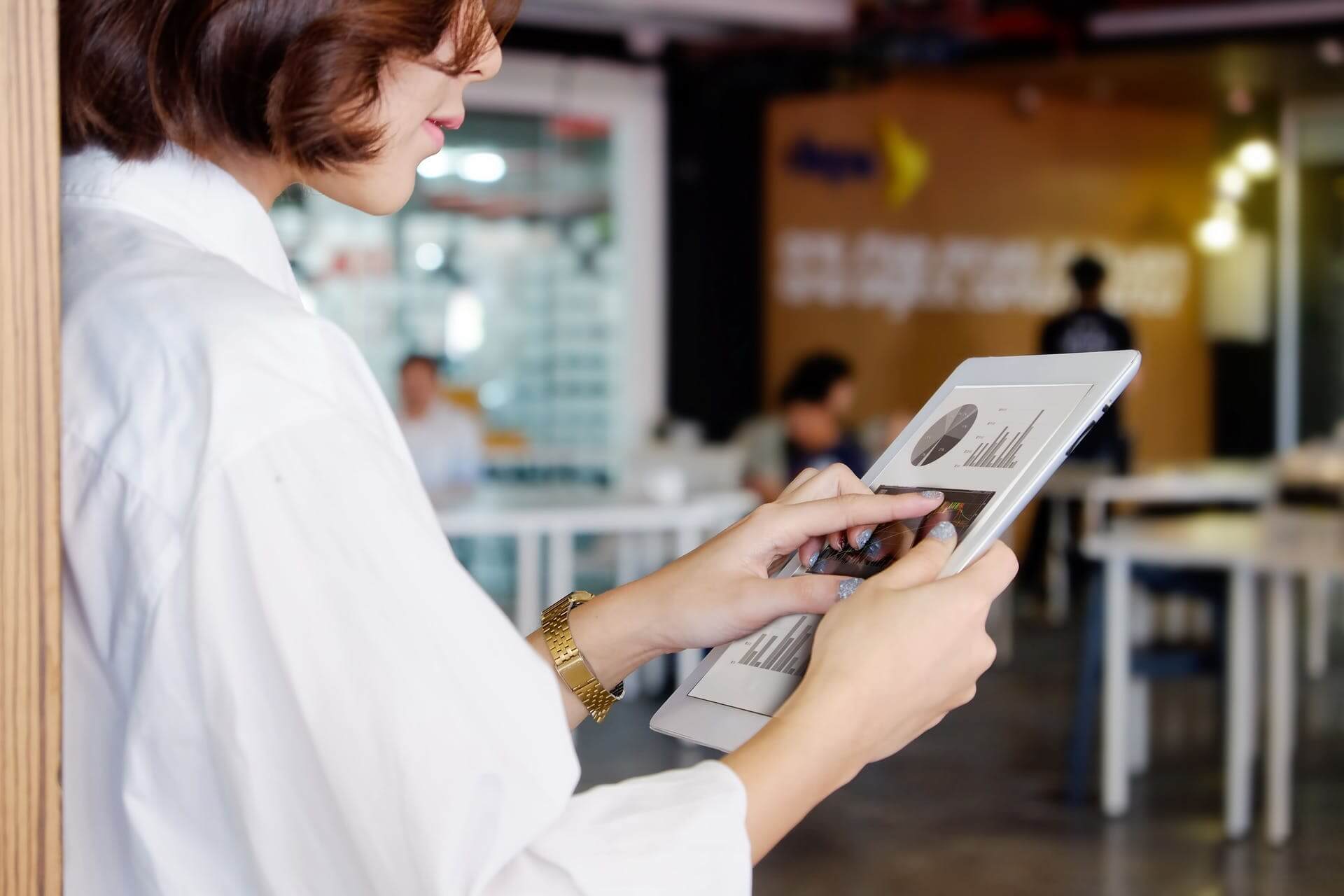 Femme avec une chemise blanche qui tient un ipad avec des graphiques