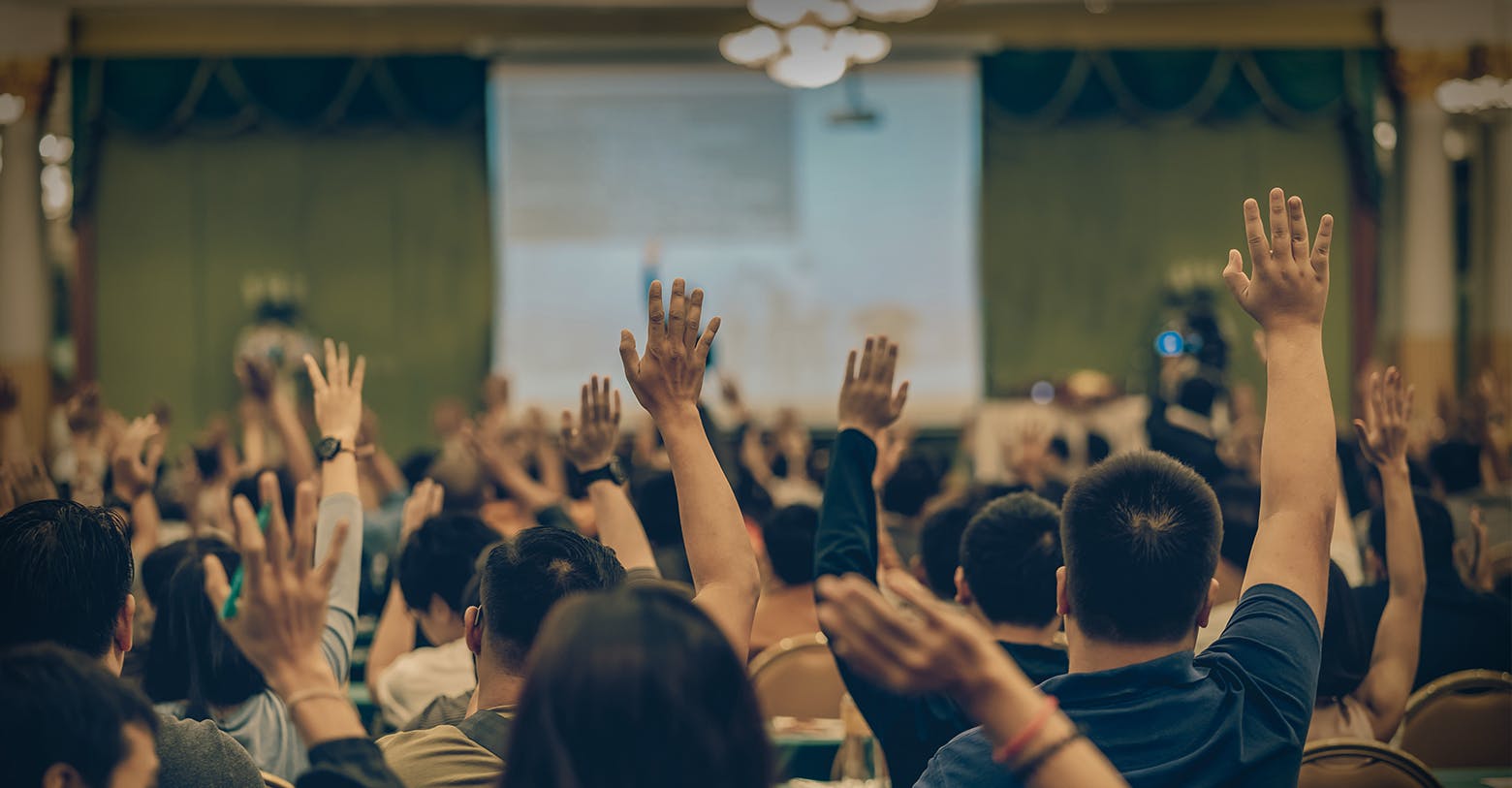  uma sala de pessoas com as mãos no ar para fazer perguntas 